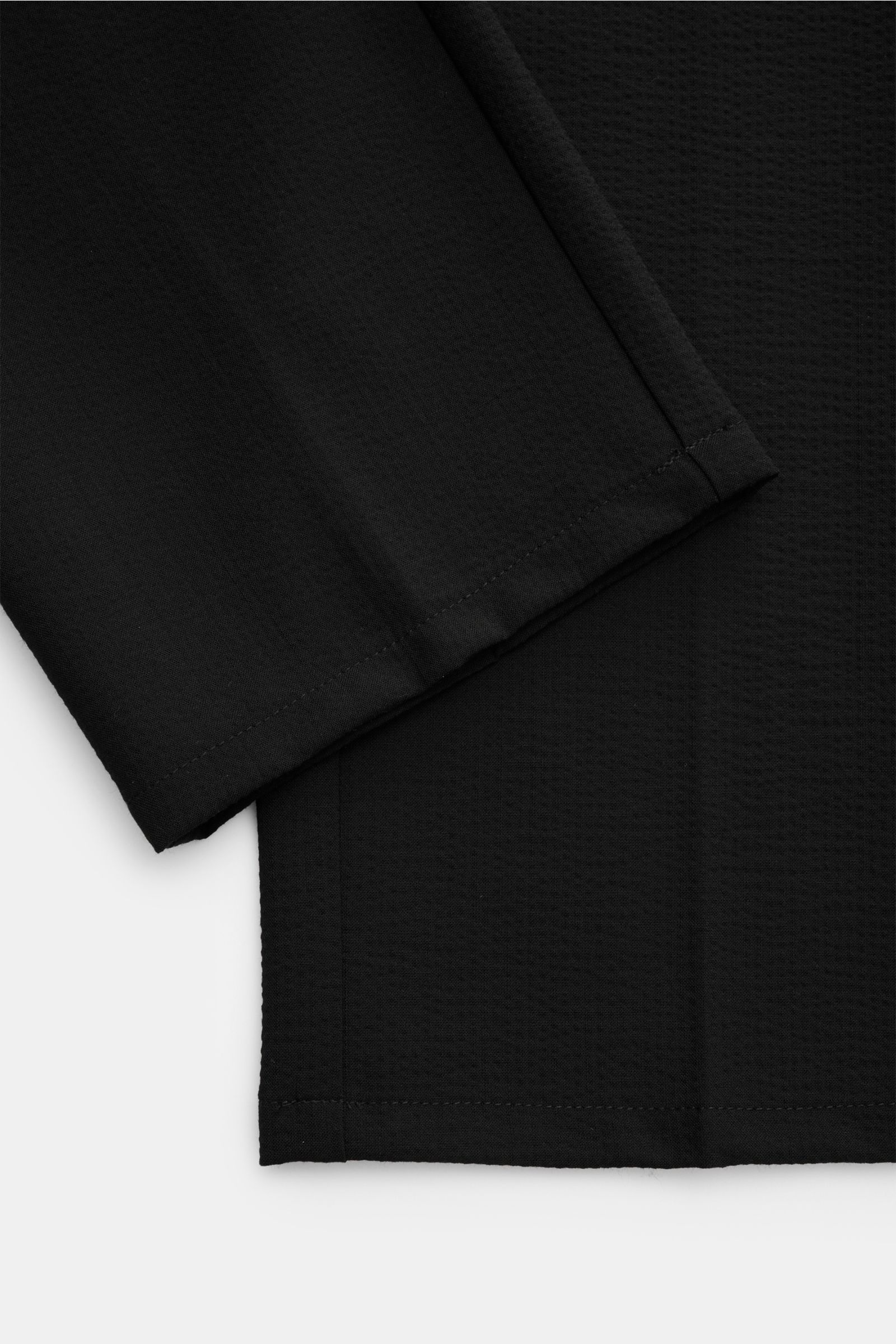 Close-up view of the hem and fabric texture of the 04651/ A trip in a bag Seersucker-Hose schwarz, made from seersucker wool and microfiber with a materialtypischer Griff, tapered fit, regular thigh width, shortened leg length, elastic waistband with inte