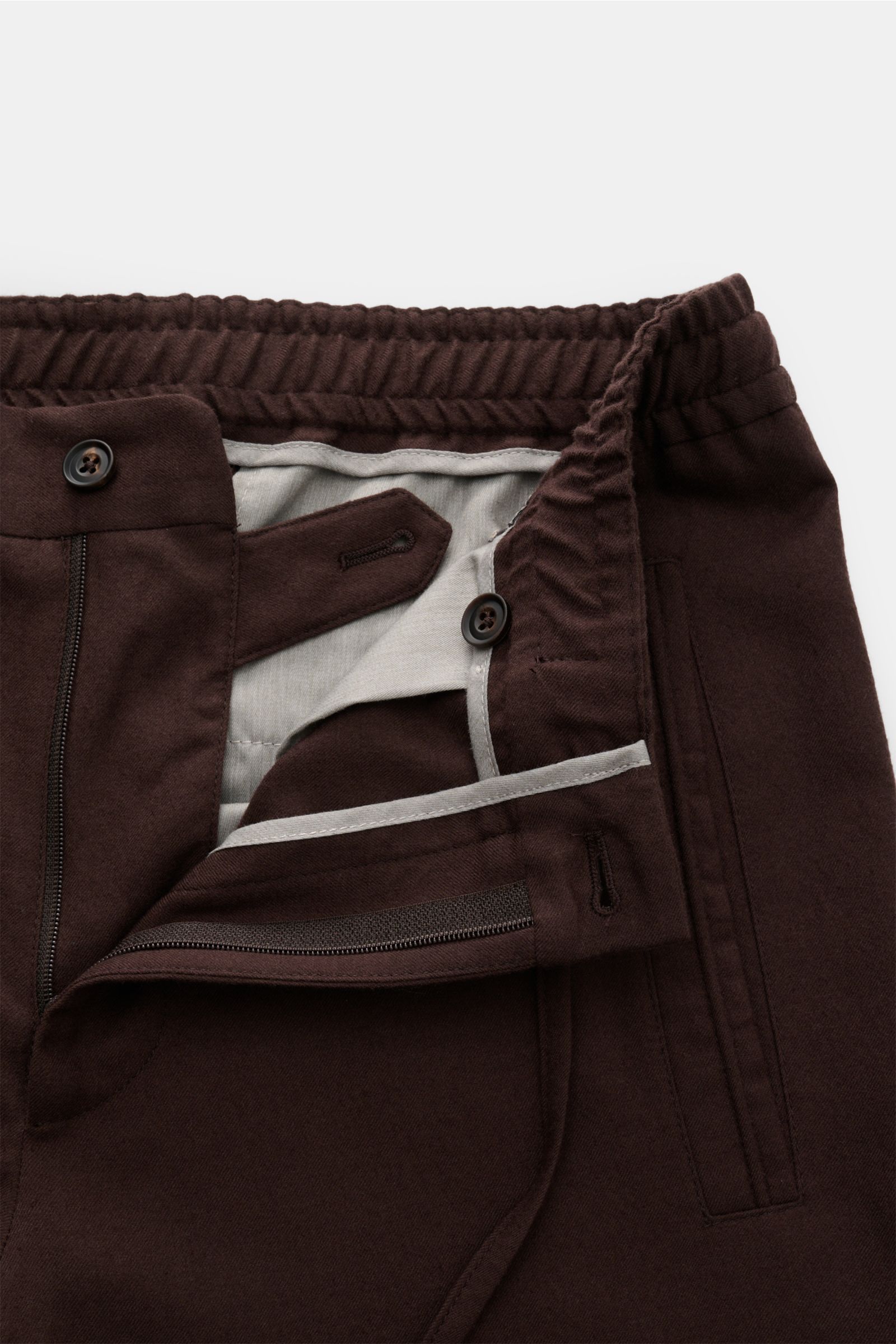 Nahaufnahme der geöffneten Corneliani Woll-Jogpants dunkelbraun aus reiner Schurwolle, softer Griff, Regular Fit, leicht schmal zulaufend, mit Reißverschluss, Bundknopf, elastischem Bund mit Tunnelzug, schrägen Leistentaschen vorne und Leistentaschen am G