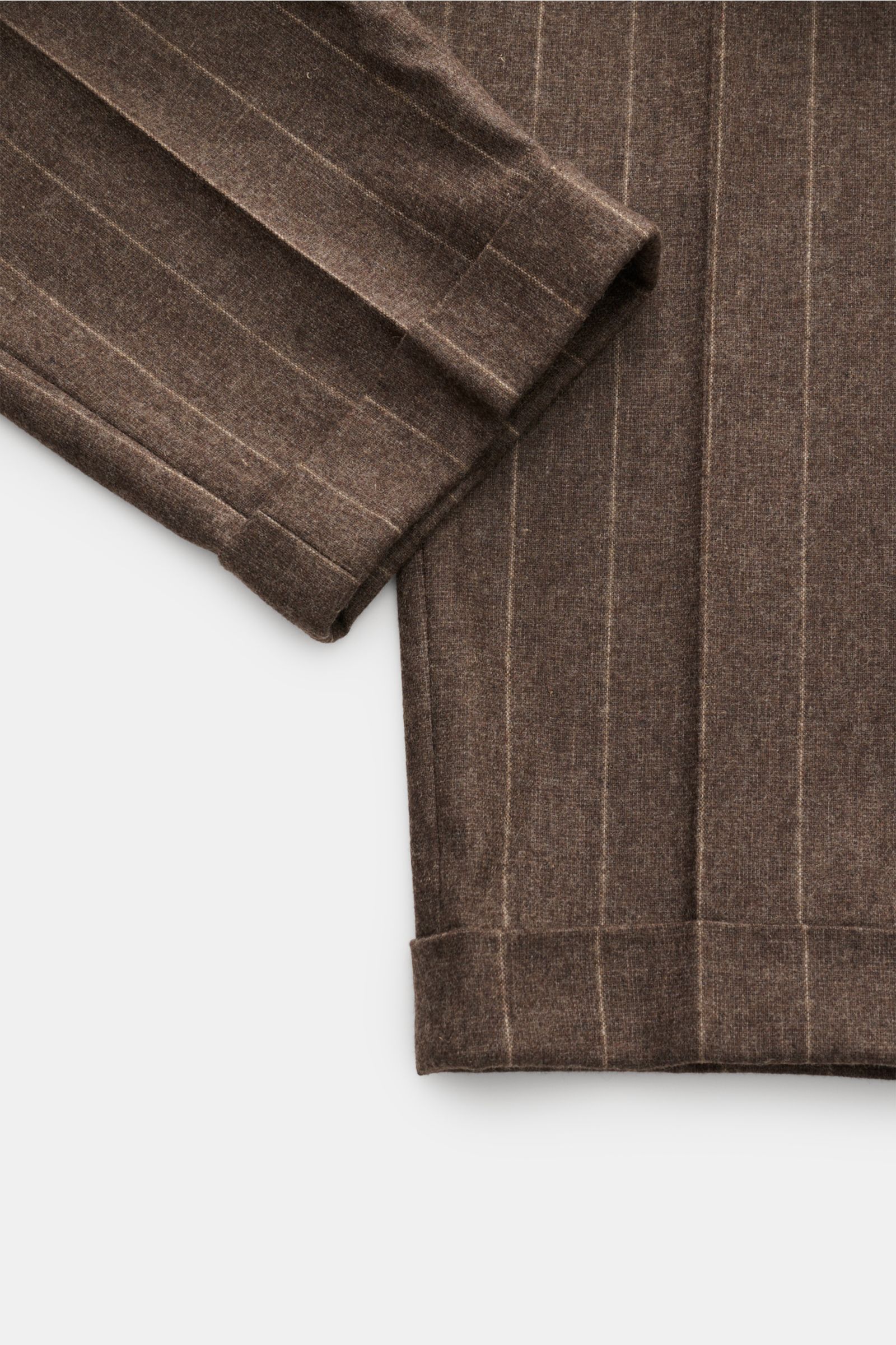 Close-up photo from above of the cuff and lower leg of the Windsor Hose 'Sapo' graubraun gestreift, a cropped, tapered wool blend trouser with chalk stripes and a soft texture.