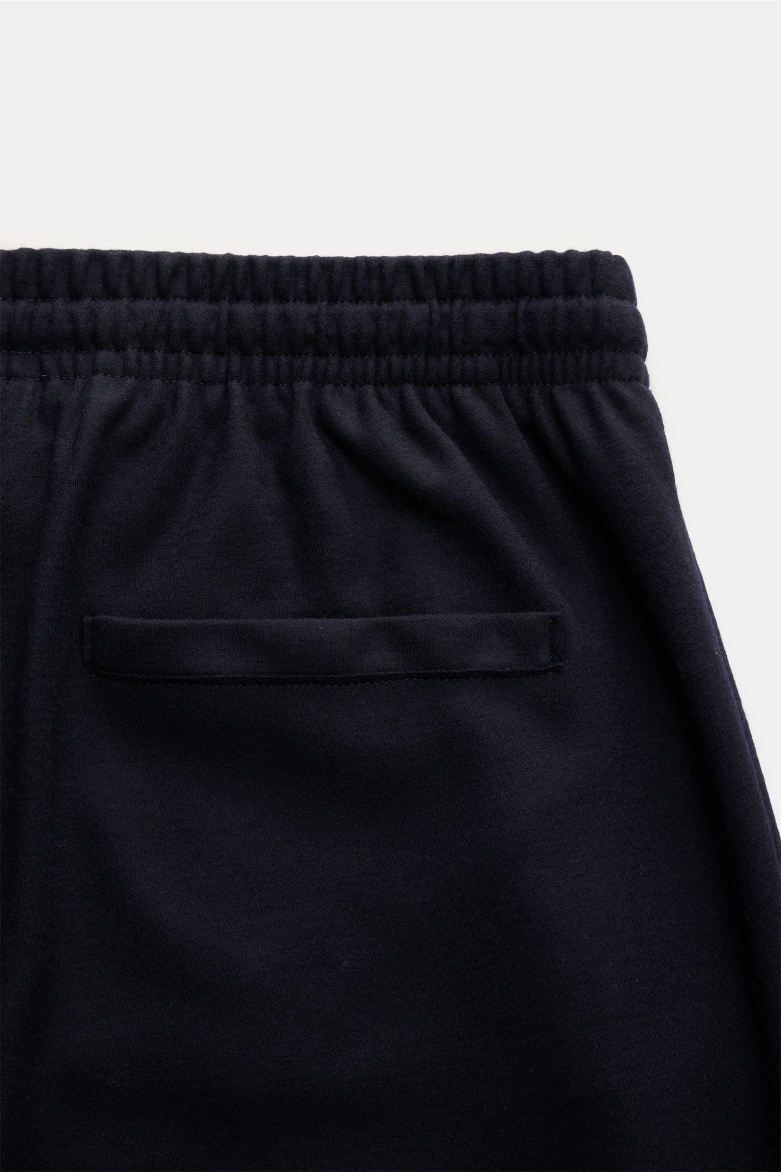 Nahaufnahme der Rückseite der Harris Wharf London Merino Jogpants navy aus superfeiner Merinowolle, schmal zulaufend mit elastischem Bund, paspelierter Gesäßtasche, fotografiert von oben.