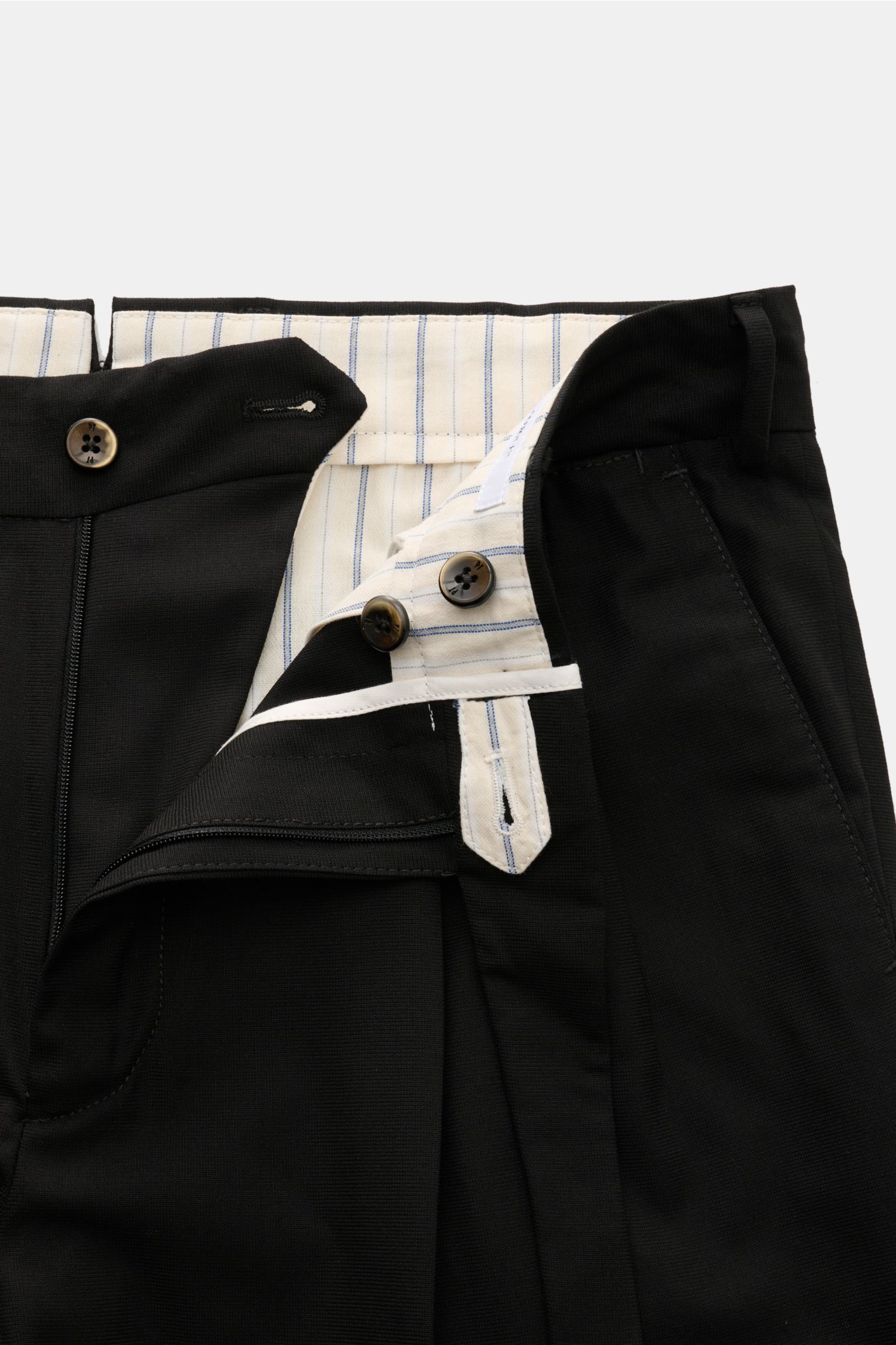 Close-up front view of PT Torino Jersey trousers 'Carrot Fit' black showing open waistband with elongated buttoned tab, zip, double pleat, and striped inner lining. With their short cut, stylish pleats and elongated buttoned tab, the jersey trousers 'Carr