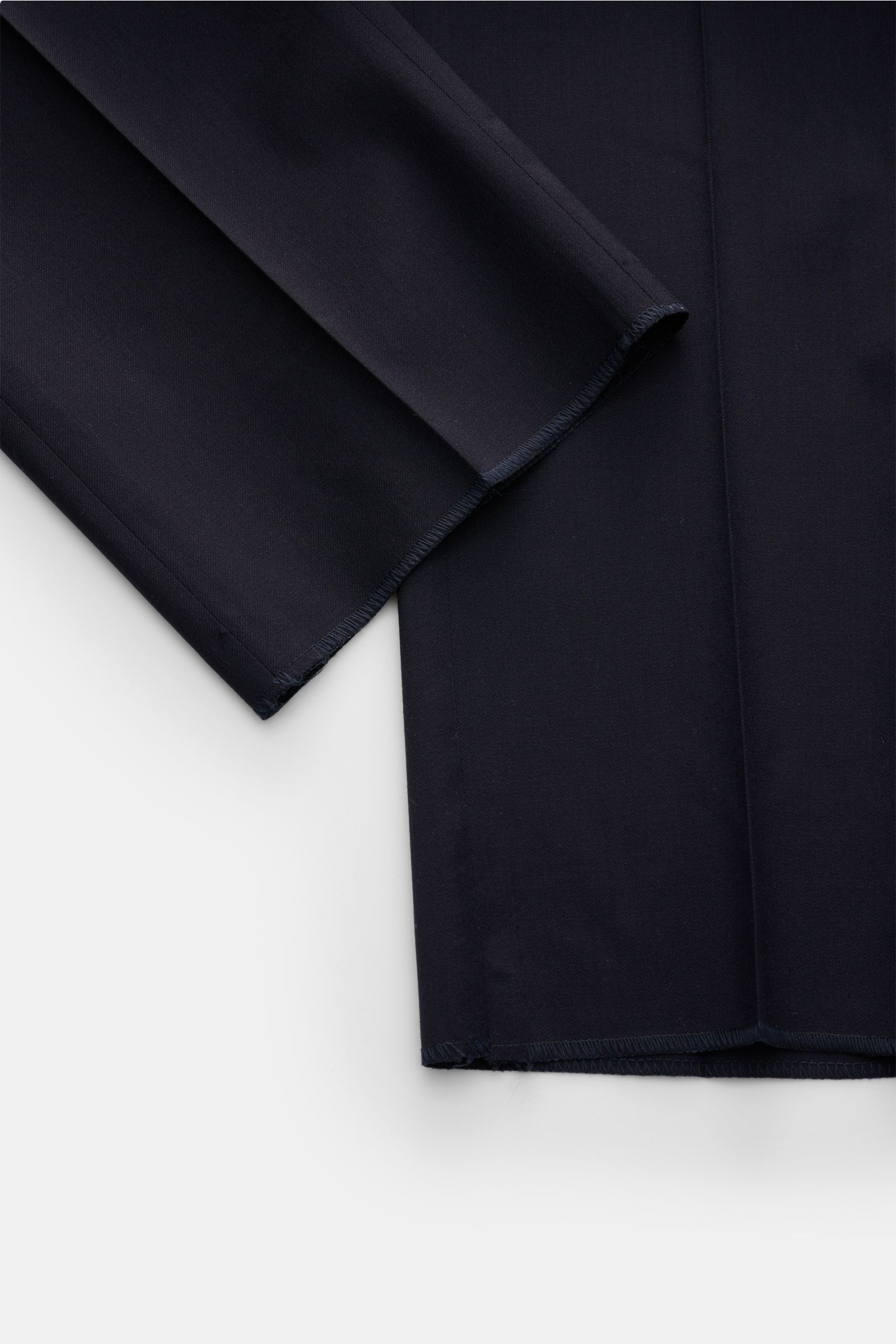 Close-up front view of navy PT Torino Wollhose 'Slim Fit' wool trousers showing fine twill fabric, soft touch, slim tapering, open hem edges. Features zipper, waistband buttons, French pockets, small watch pocket, slim piped back pockets with buttons.