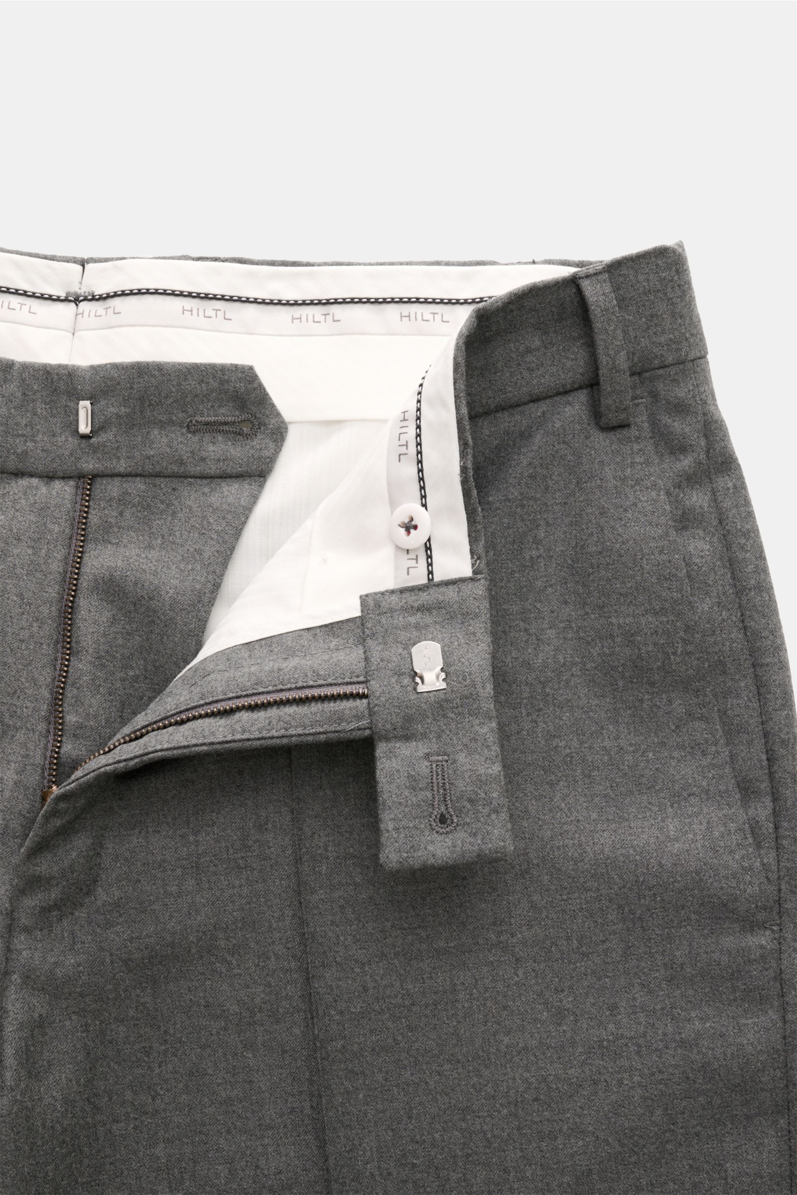 Close-up front view of Hiltl Wollhose 'Piacenza' grau meliert in grey melange wool-cashmere twill, showing zipper, button, waistband, and pockets.

Office Essential: Die HILTL Hose 'Piacenza' vereint präzise Schneiderkunst mit modernem Komfort und wird