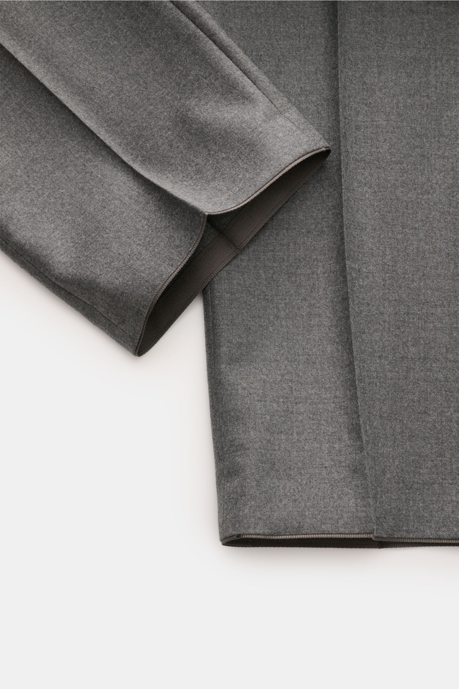 Close-up front view of the Hiltl Wollhose 'Piacenza' grau meliert showing the soft grey melange wool-cashmere fabric and open hem edge. Office Essential: Die HILTL Hose 'Piacenza' vereint präzise Schneiderkunst mit modernem Komfort und wird so zum unverzi