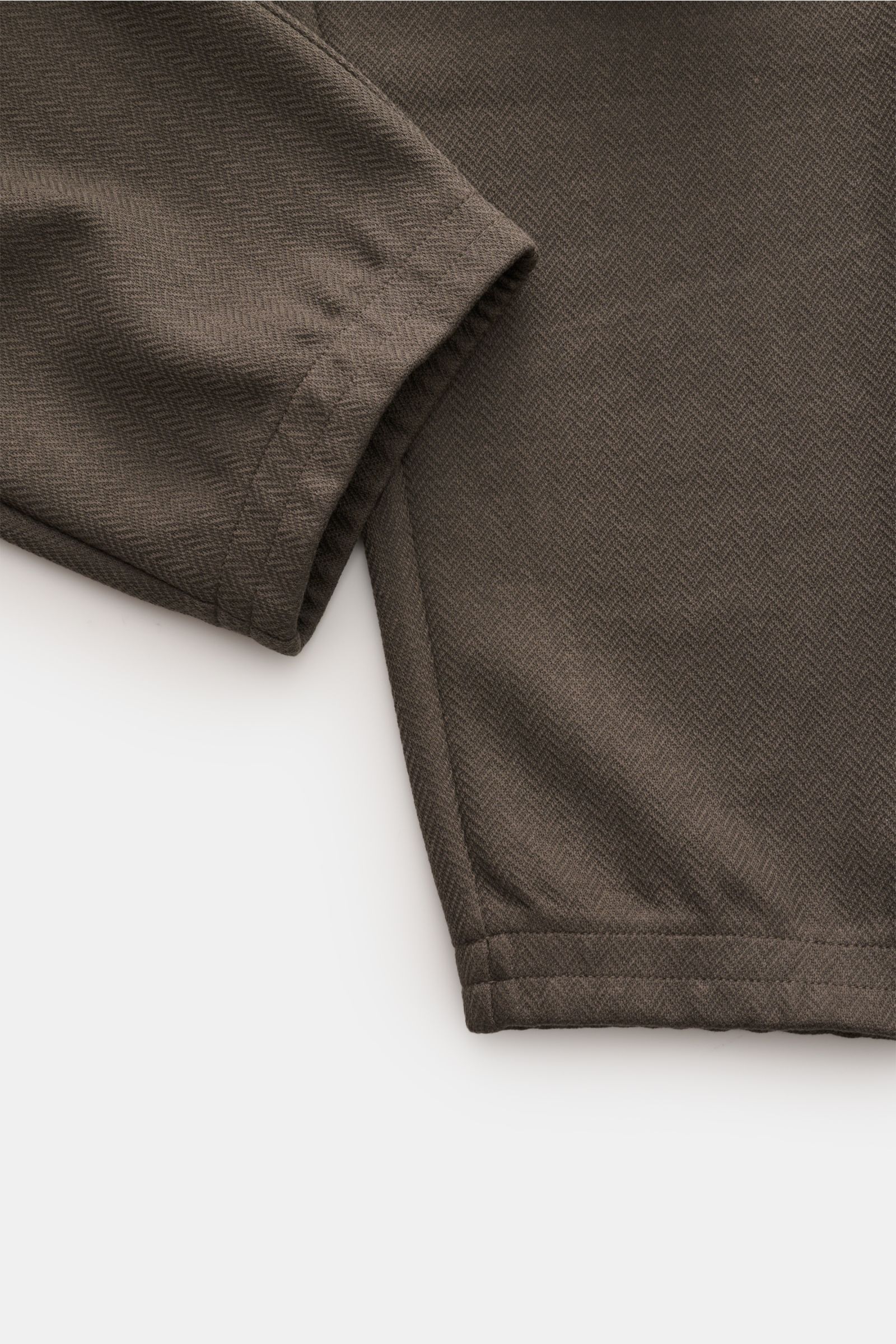 Nahaufnahme der dunkelgrauen Emporio Armani Jogpants aus Baumwoll-Lyocell-Mix mit leicht strukturierter Oberfläche, elastischem Bund, schmal zulaufendem Bein und elastischem Beinabschluss, fotografiert aus seitlicher Perspektive.