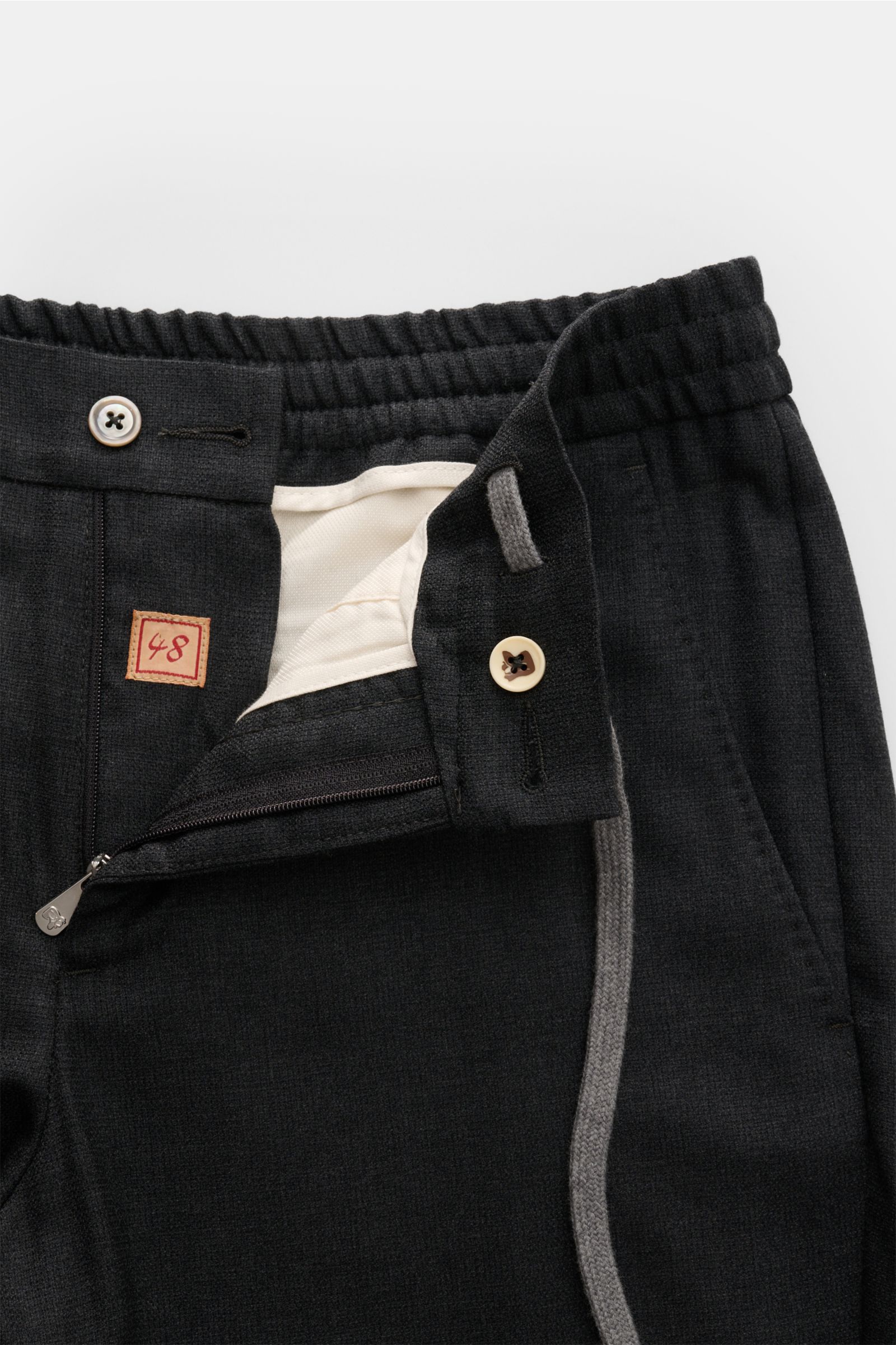 Close-up front view of Marco Pescarolo Woll-Jogpants 'Caracciolo' anthrazit showing zipper, button, elastic waistband, and fabric texture.

Die elegante Jogpants 'Caracciolo' vom italienischen Modelabel MARCO PESCAROLO vereint edle Schurwolle zu höchst