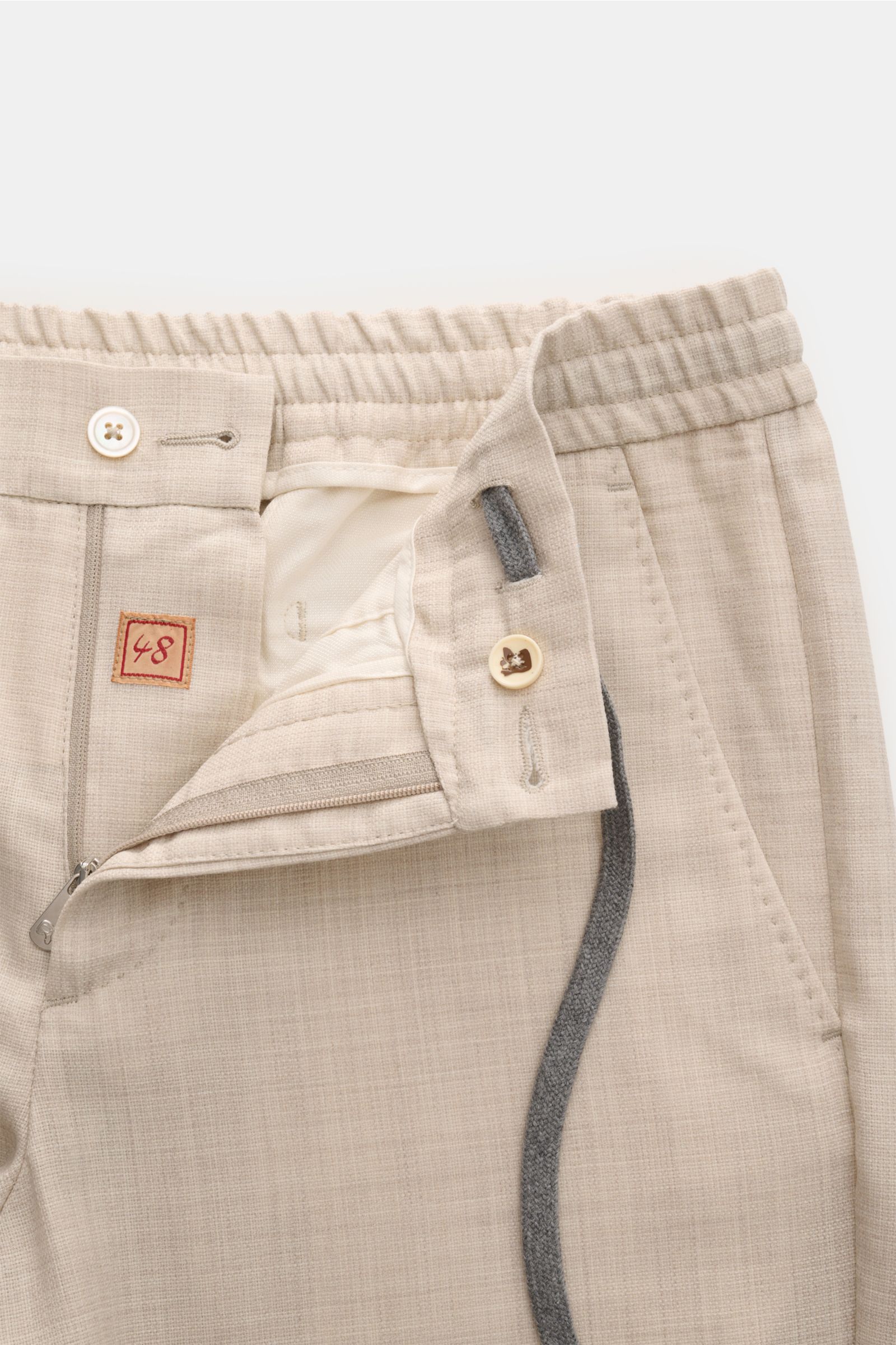 Close-up front view of Marco Pescarolo Woll-Jogpants 'Caracciolo' beige meliert showing elastic waistband, button, zipper, and drawstring.

Die elegante Jogpants 'Caracciolo' vom italienischen Modelabel MARCO PESCAROLO vereint edle Schurwolle zu höchst