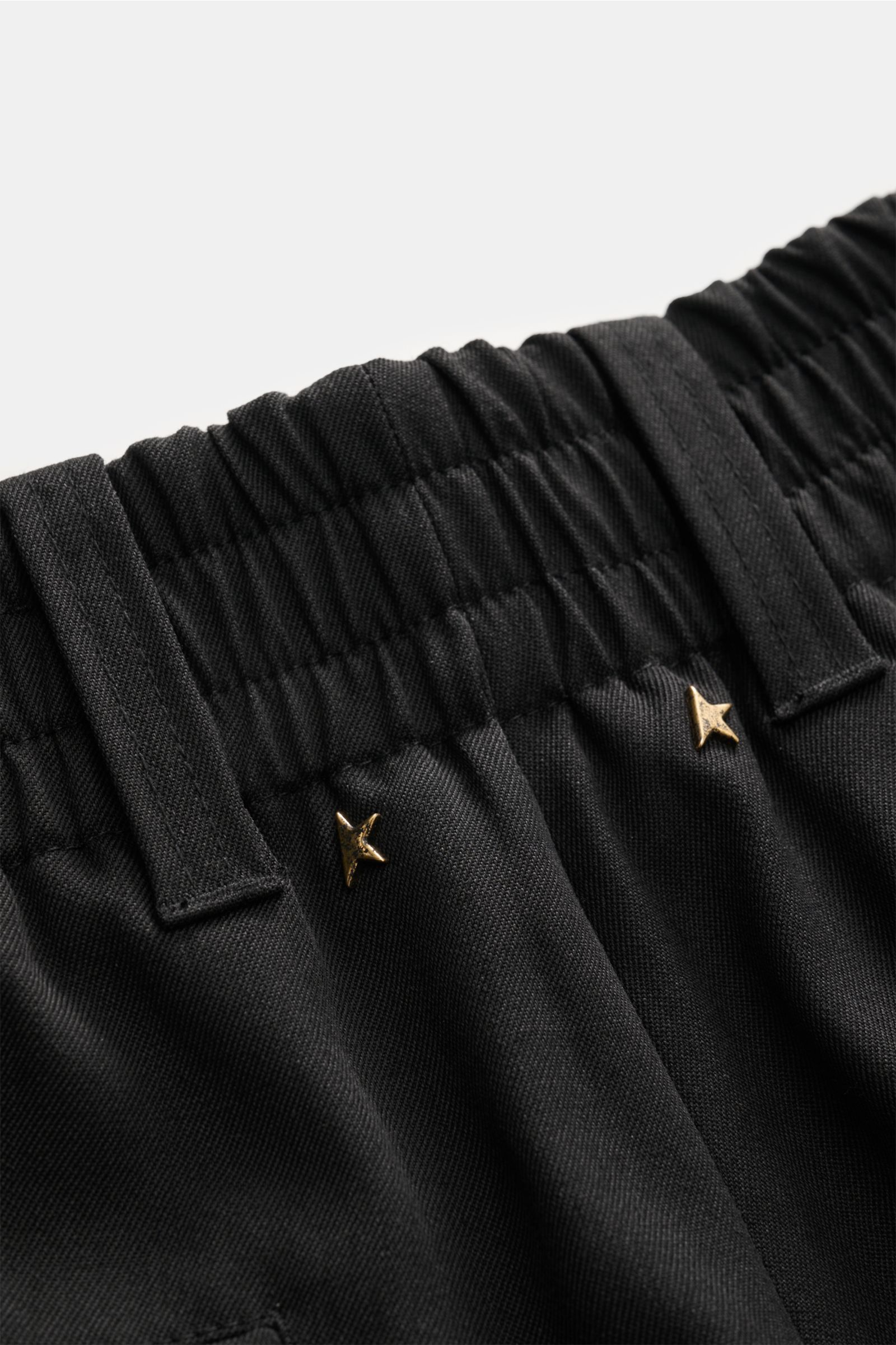 Close-up front view of Golden Goose Wool trousers black, showing the elasticated waistband with belt loops and gold star rivet detail, made of twill pure virgin wool with a robust feel, double pleat, French pockets, hip pockets on the seat, tapered fit, a