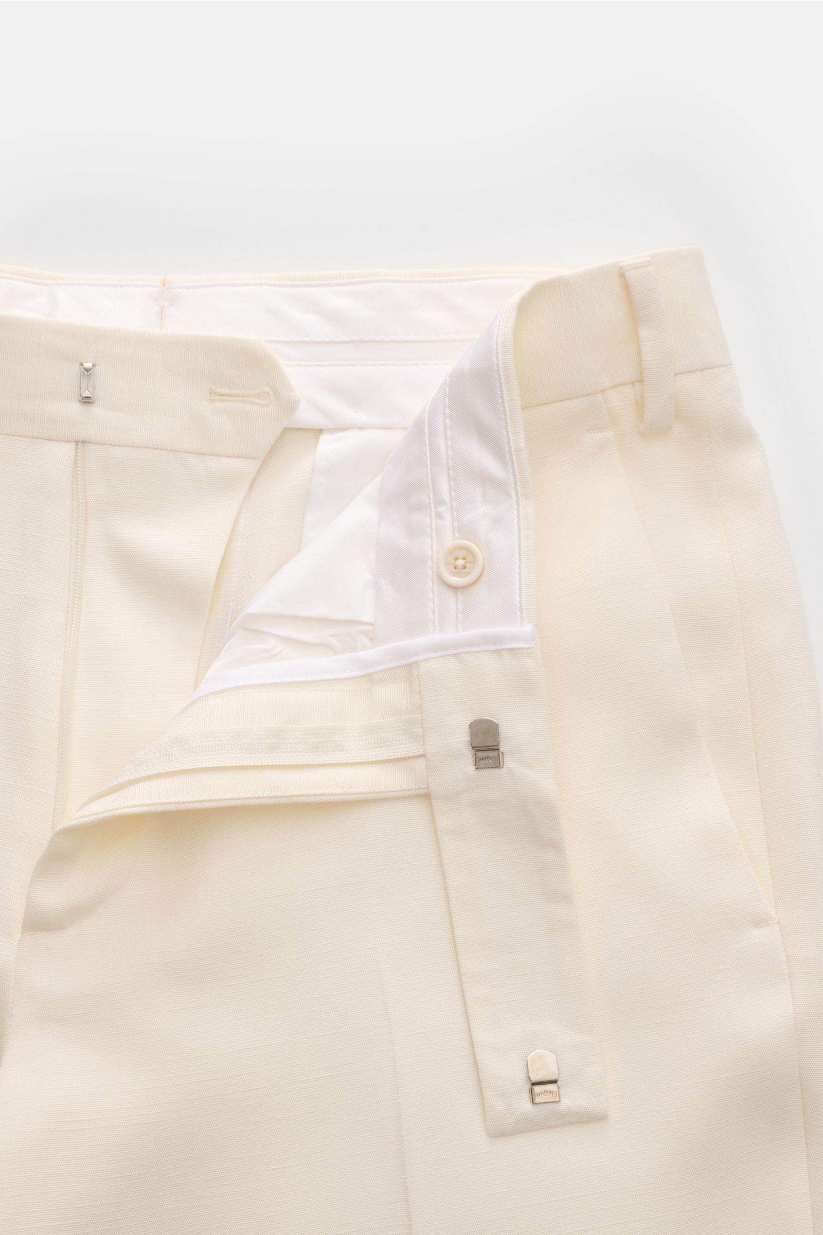 Lardini Hose creme, Detailaufnahme von oben, edler Zwirn aus Viskose mit Seide, Regular Fit, Reißverschluss, Bundhaken, französische Taschen, kleine Uhrentasche, paspelierte Gesäßtaschen mit Knopf, offene Länge, sichtbare Titerschwankungen im Gewebe.