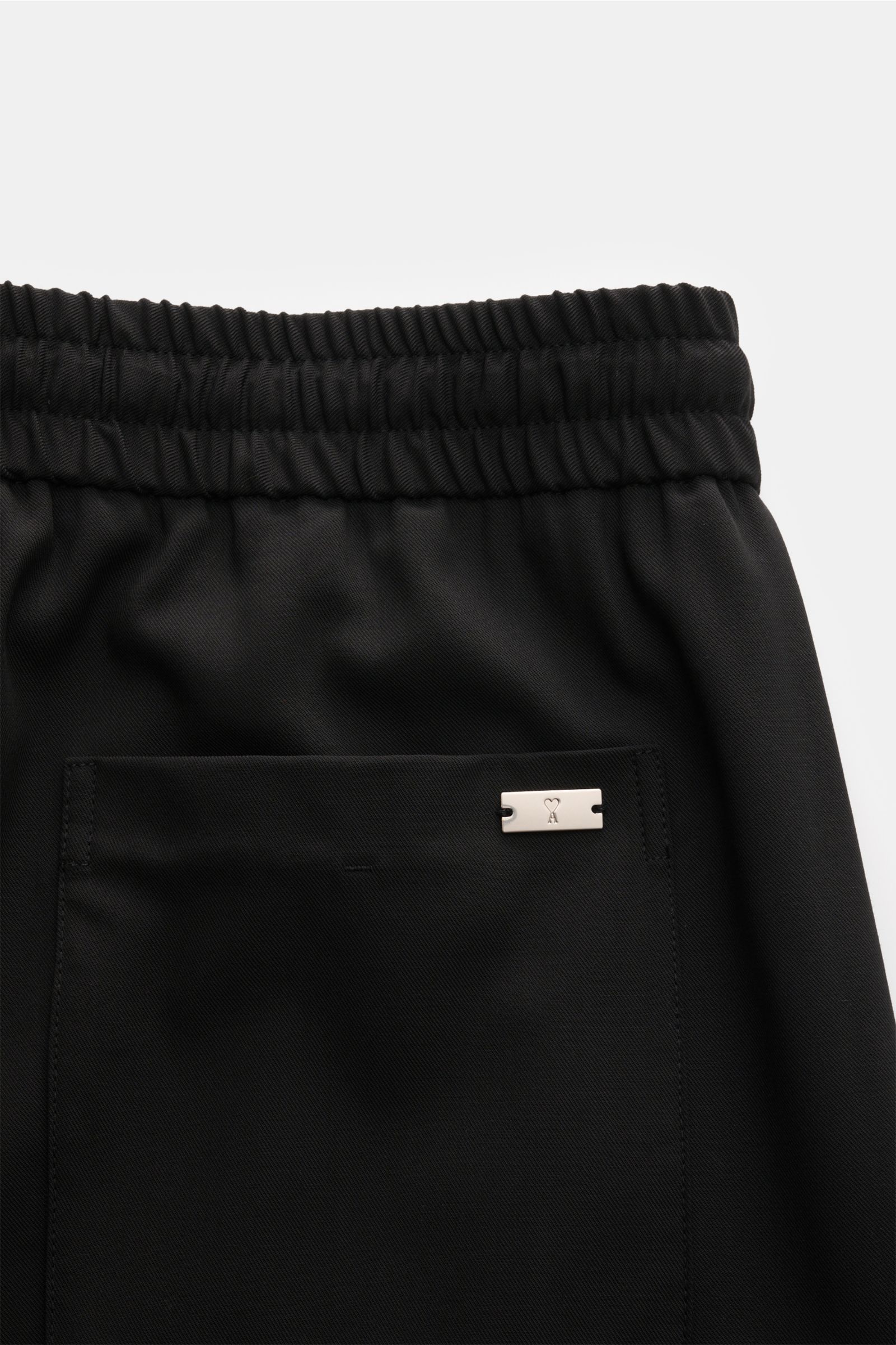 Close-up image of Ami Paris Jogger pants black from the back, showing the elasticated waistband with drawstring, patch back pocket with a small metal logo plate. Trendy oversized fits are easy to style with these relaxed fit jogger pants from AMI PARIS – 