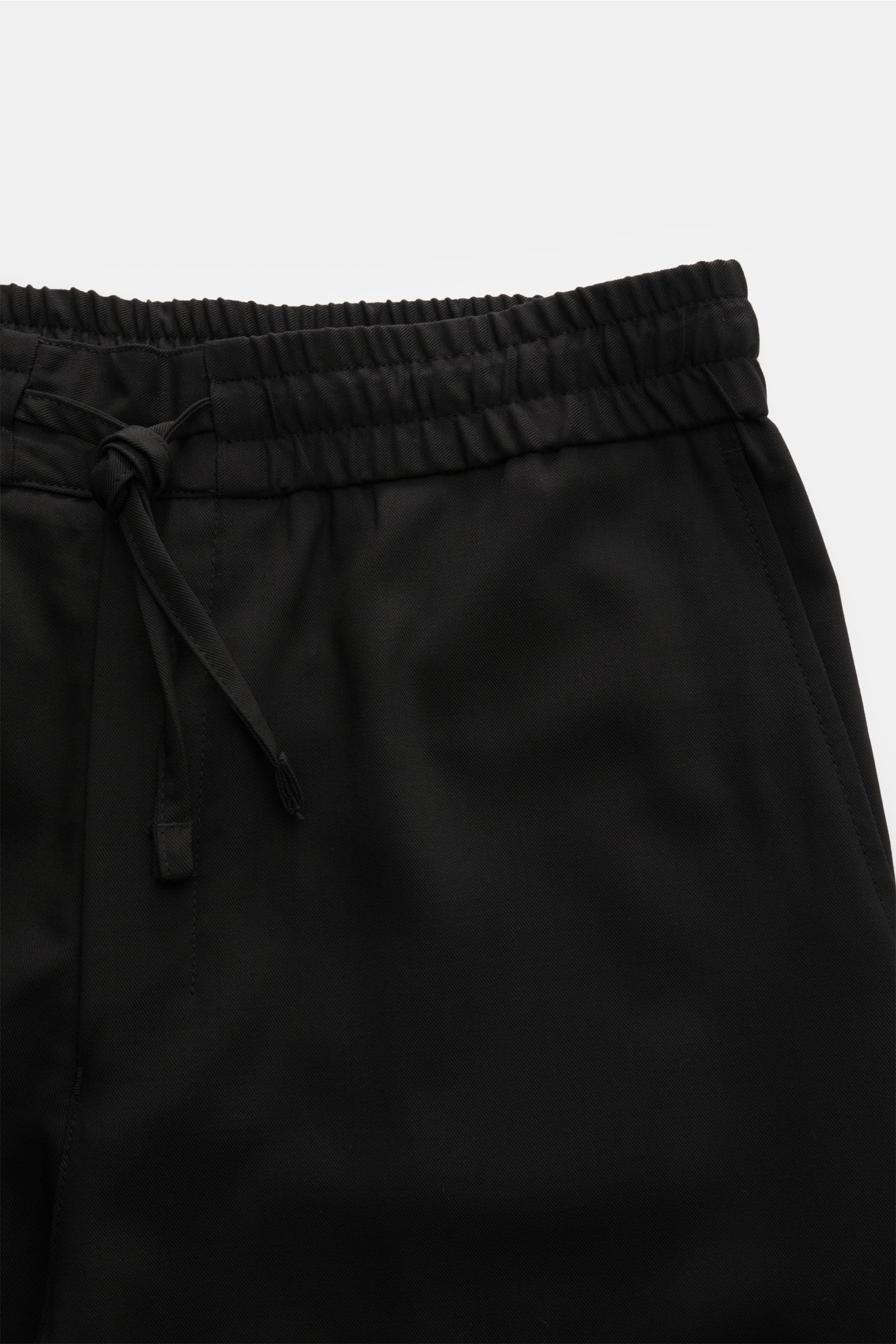 Close-up front view of Ami Paris Jogger pants black, showing elasticated waistband with drawstring, zip and waist button, French pockets, made from pure virgin wool, lightweight with a cool feel, loose fit and slightly tapered cut, high waist, ideal for w