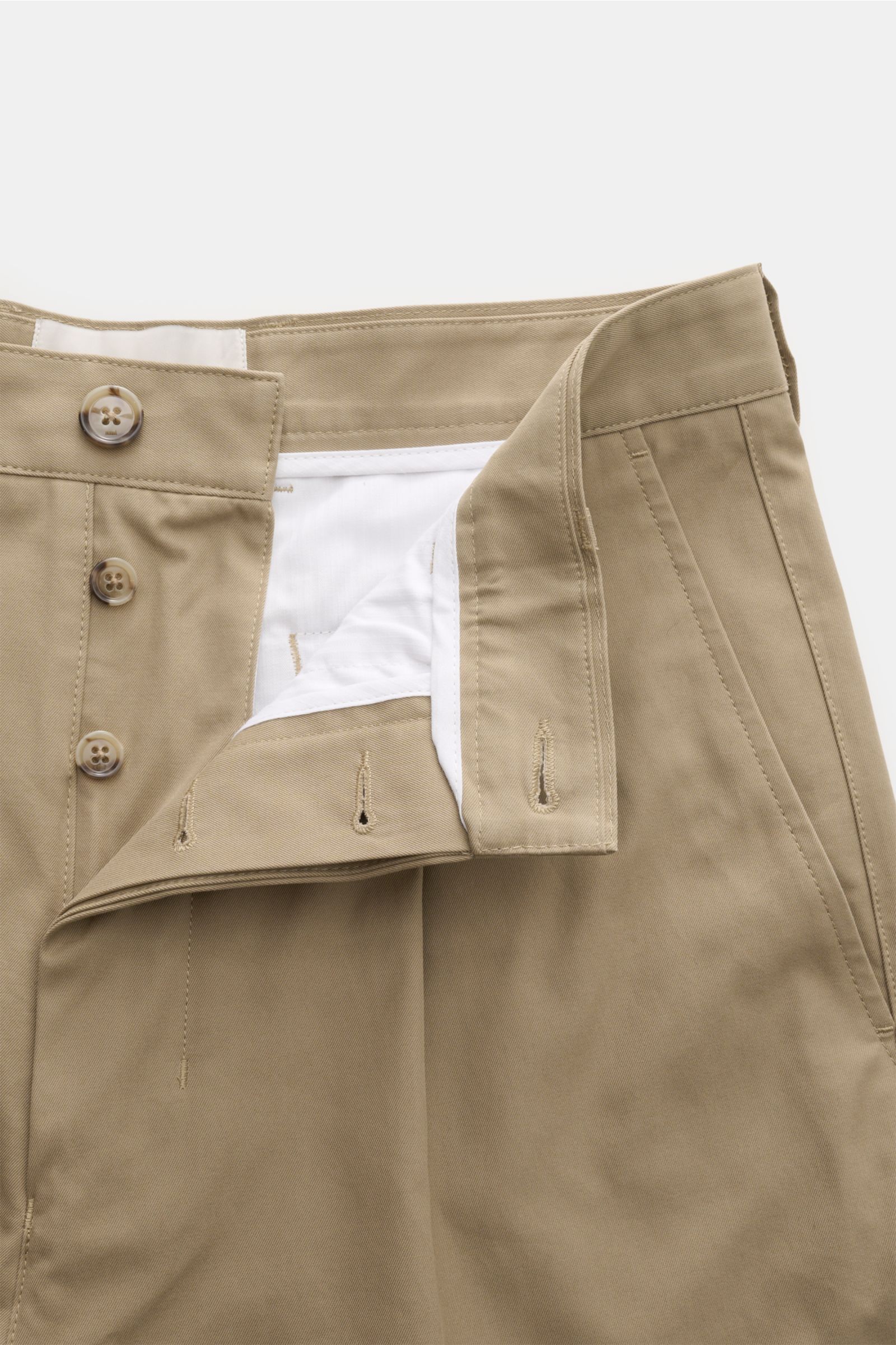 Ami Paris Chino 'Carrot Oversized' sand, frontale Nahaufnahme mit offenem Button Fly, hohem Bund, fixiertem Saumaufschlag, Taschen, reine Baumwolle.