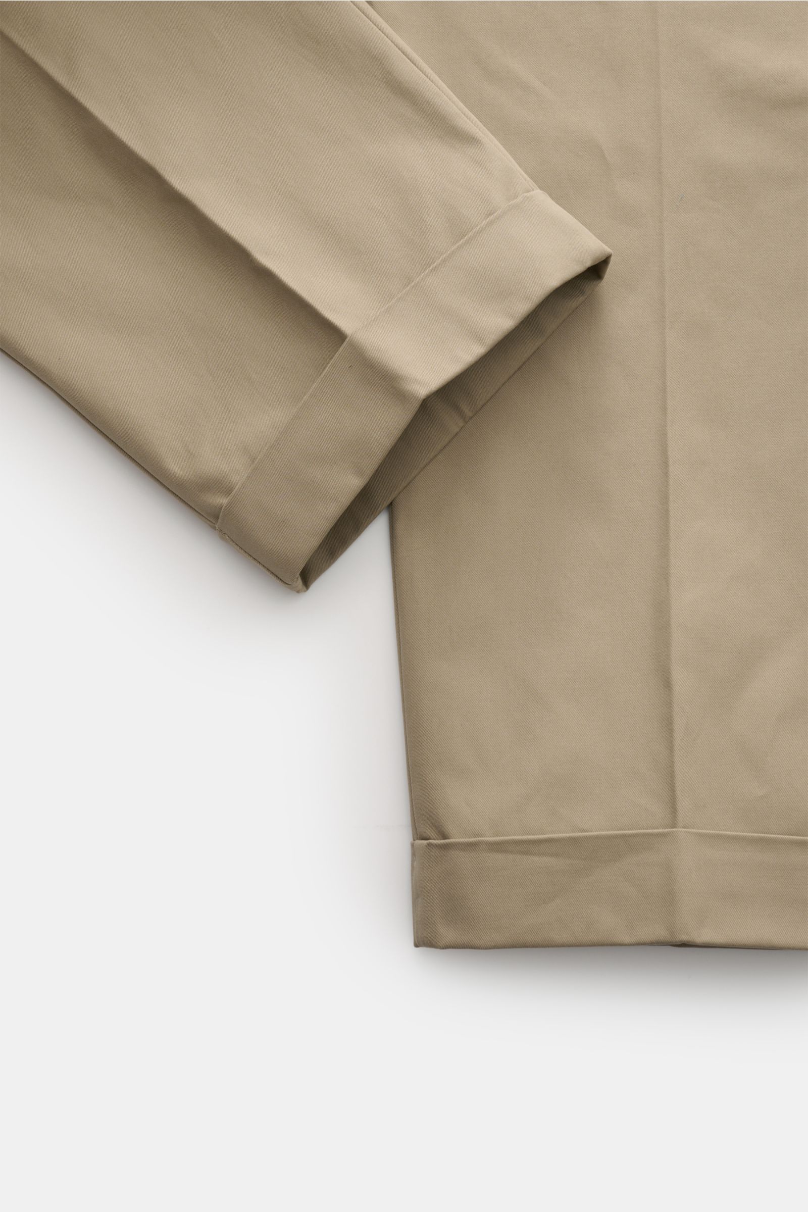 Nahaufnahme der fixierten Saumaufschläge der Ami Paris Chino 'Carrot Oversized' sand mit kurzem Schnitt und hochwertiger Baumwolle, seitliche Perspektive.