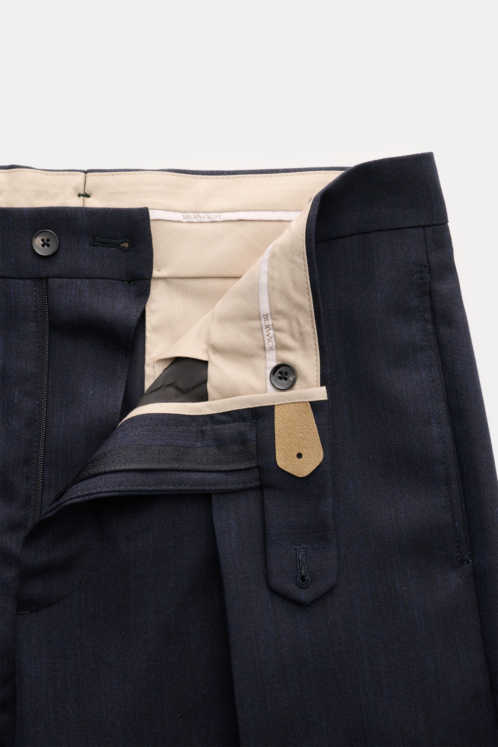 Close-up front view of Berwich Hose 'Chiaia' navy meliert showing open waistband, button, zipper, and beige interior lining. The Berwich Hose 'Chiaia' navy meliert features a modern tapered fit with a single pleat, made from a wool, silk, and linen blend 