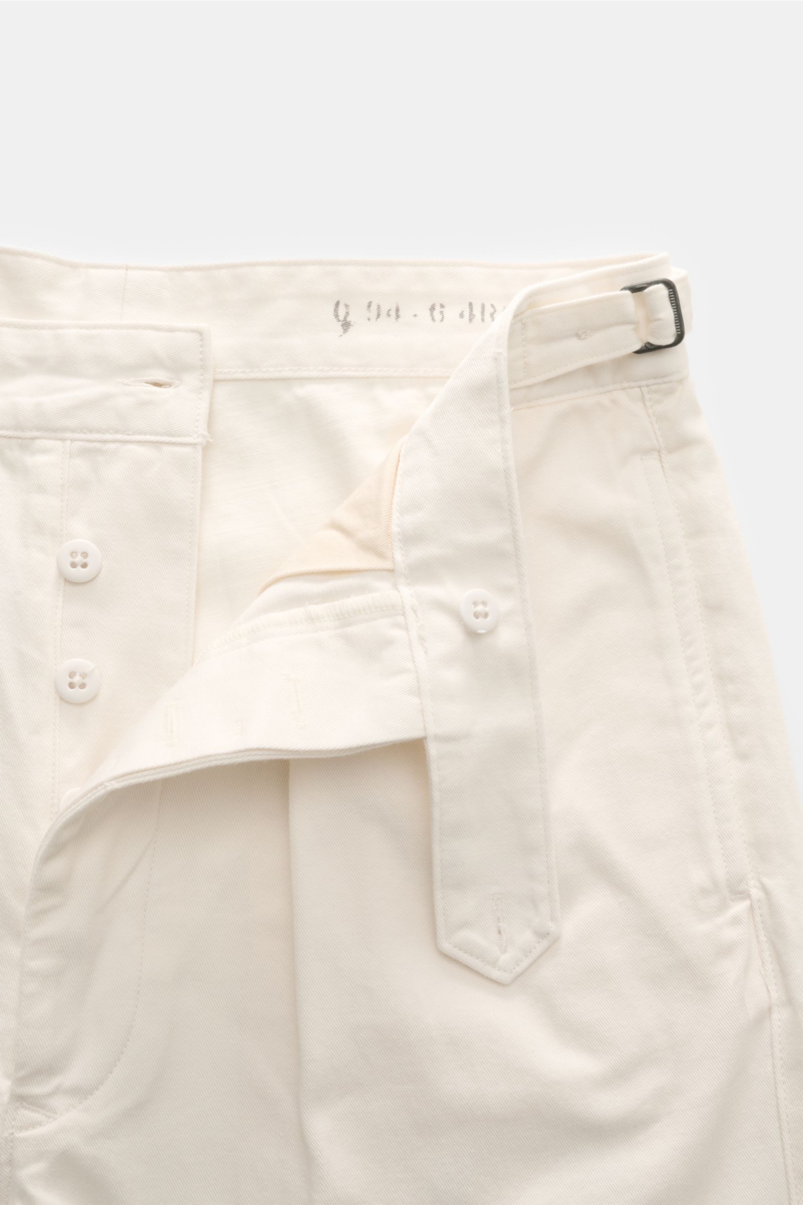 Nahaufnahme der Polo Ralph Lauren Baumwollhose creme von vorne oben, geöffnet mit Side Adjuster, Knöpfen und Bundknopf aus weichem Twill.