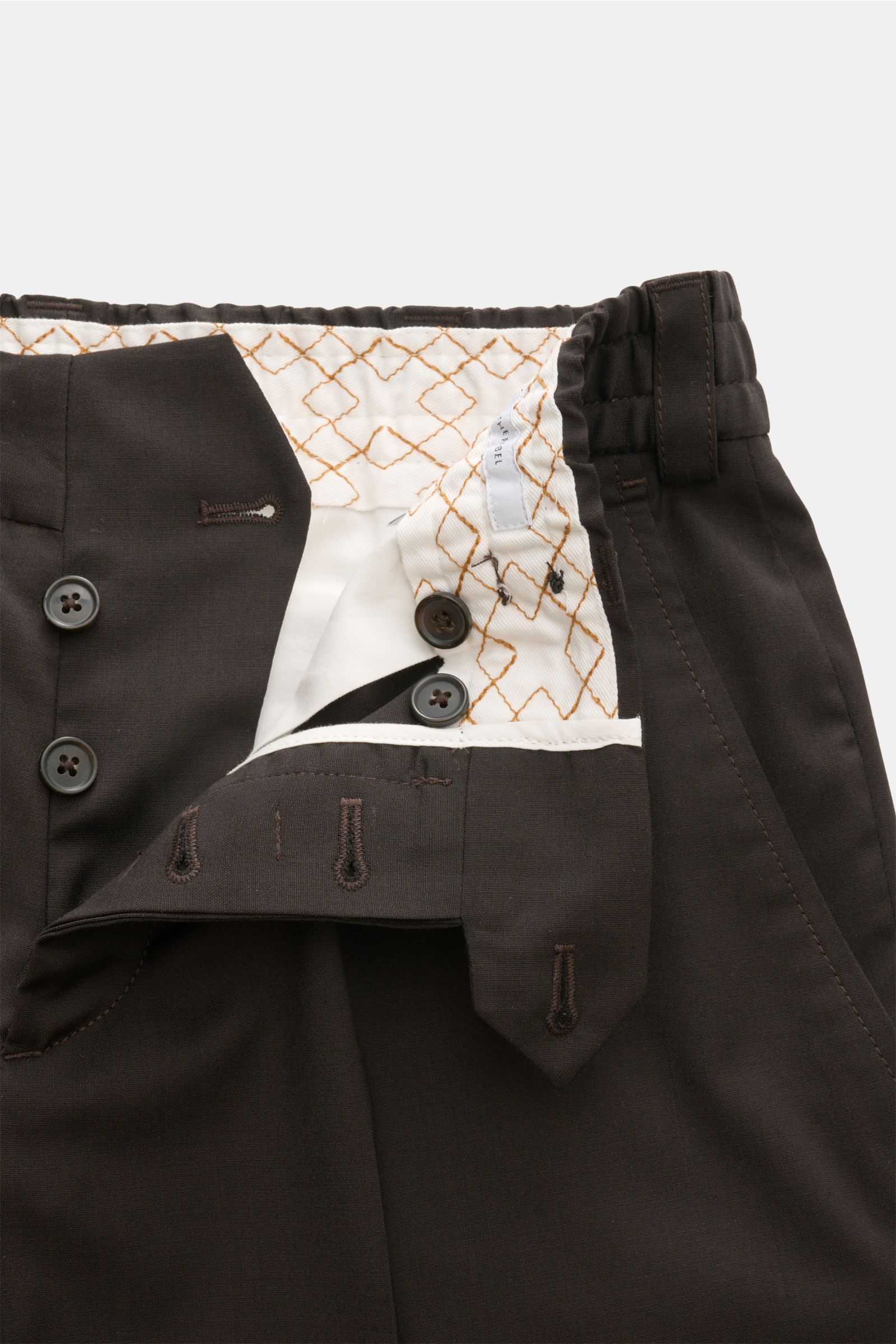 Close-up front view of PT Torino Trousers 'The Rebel' dark brown showing button fly, waist button, and patterned inner lining. Lightweight wool-microfibre blend, soft feel, Rebel Fit, regular thigh width, ankle length, French pockets, back pockets with bu