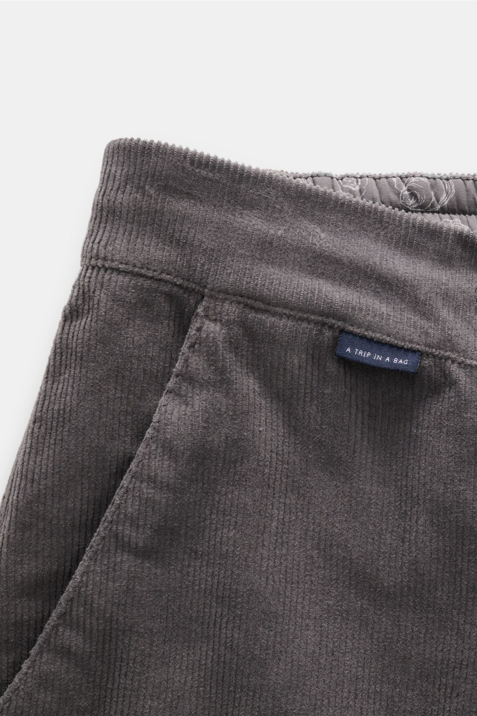 Close-up front-side view of 04651/ A trip in a bag Cord-Joggpants 'Smart Cord Cargo' oliv made of soft cotton fine corduroy with a blue logo label.