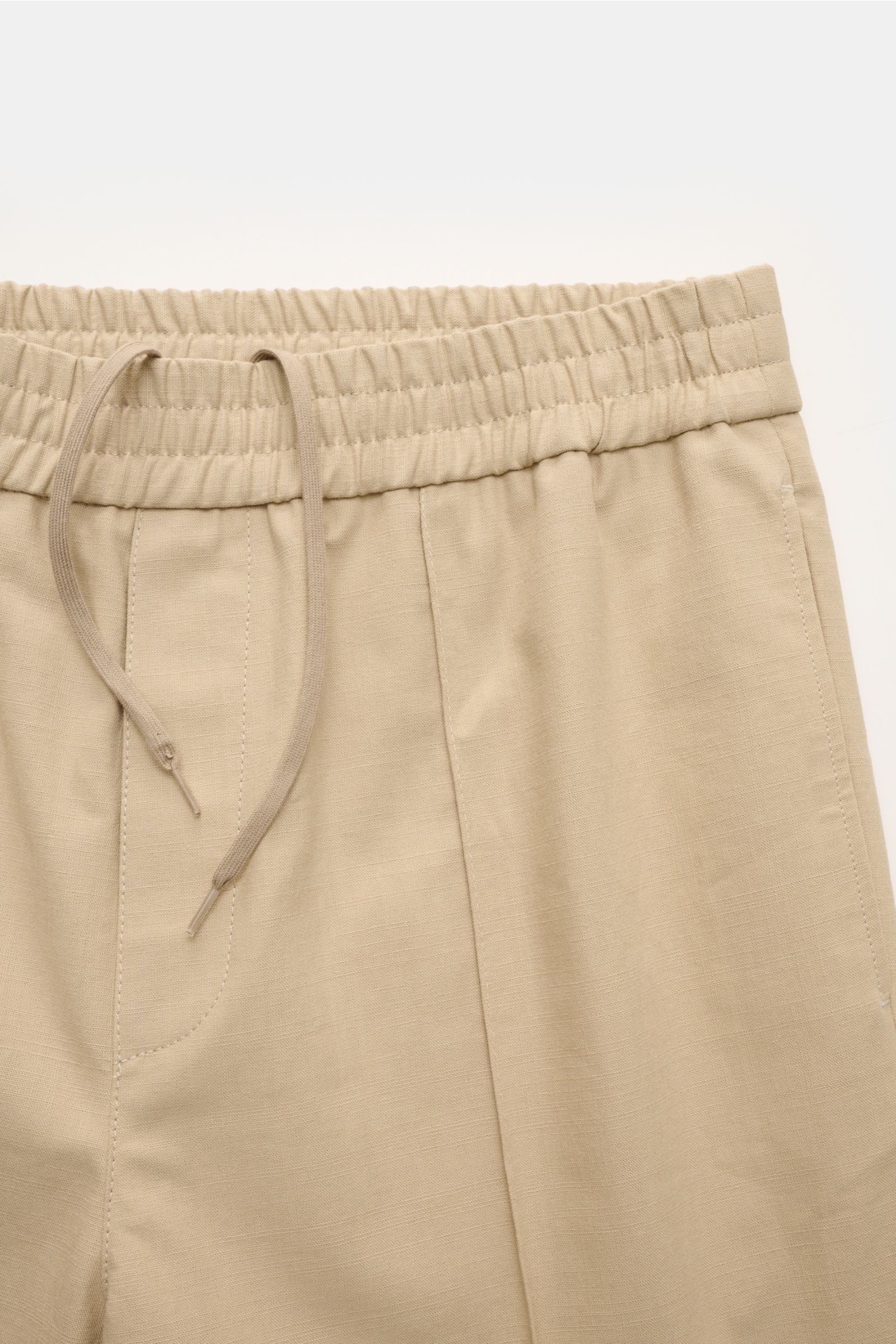 A.P.C. Joggpants 'Pieter' beige in pure cotton, close-up view. Features elastic waistband, tapered fit, and stitched crease.