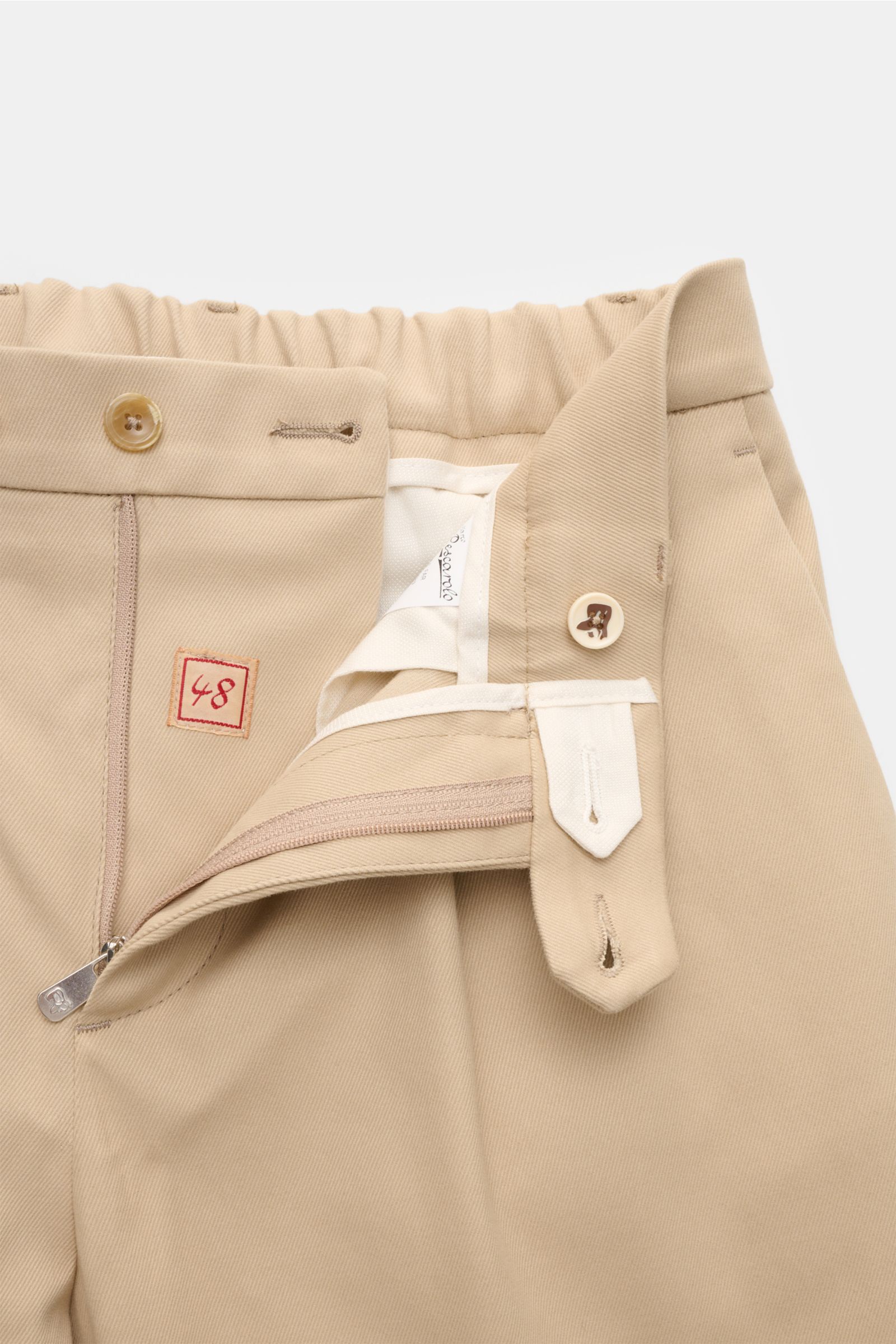 Close-up front view of Marco Pescarolo Chinos 'Far' beige showing the waistband with elastic back, zipper, button closure, and inner label. Die softe Chino 'Far' aus dem Hause MARCO PESCAROLO vereint Komfort aus edlem Baumwoll-Mix mit höchster neapolitani