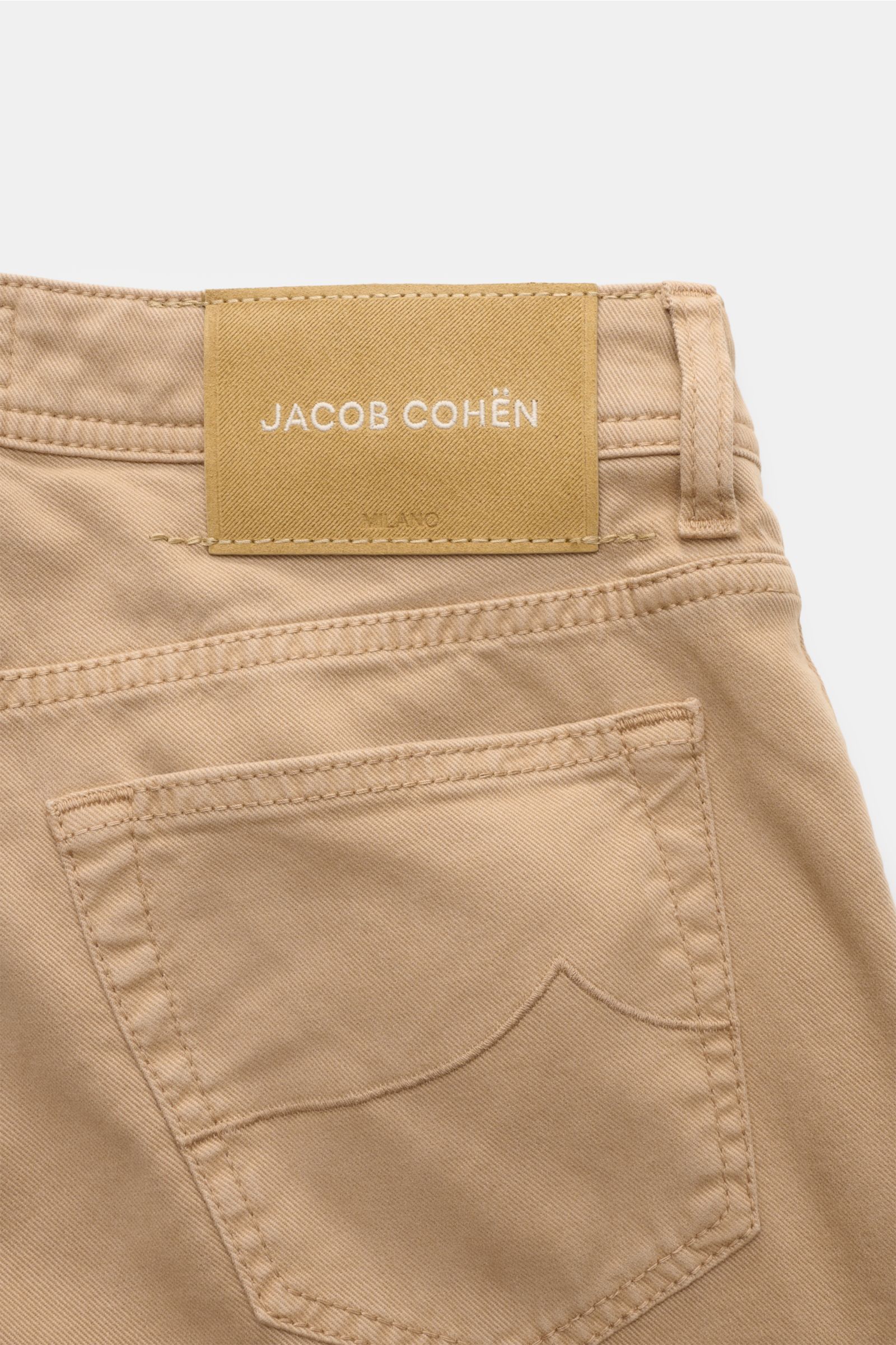 Close-up rear view of the beige Jacob Cohen Hose 'Bard' showcasing the classic five-pocket slim fit design with tonal stitching, button fly, elastic cotton-lyocell twill, coin pocket with initial, and tonal leather patch. Setzen Sie Anspruch auf Stil u