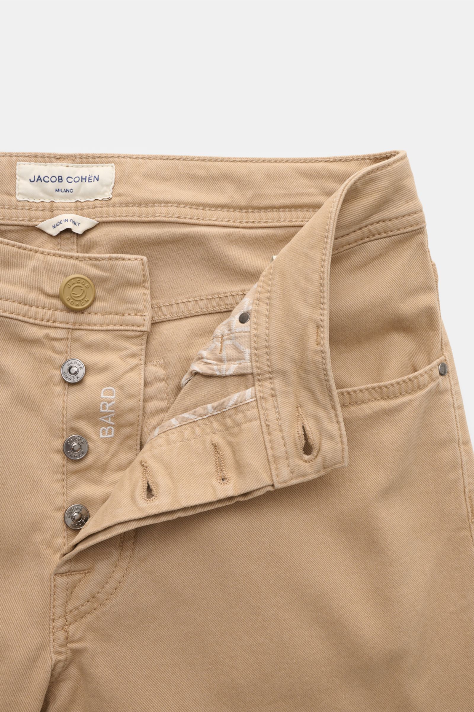 Close-up front view of Jacob Cohen Hose 'Bard' beige showing slim fit five-pocket style with button fly, tonal stitching, and leather patch.

Setzen Sie Anspruch auf Stil und Qualität mit der klassischen Five-Pocket-Hose 'Bard' von JACOB COHEN im Slim 