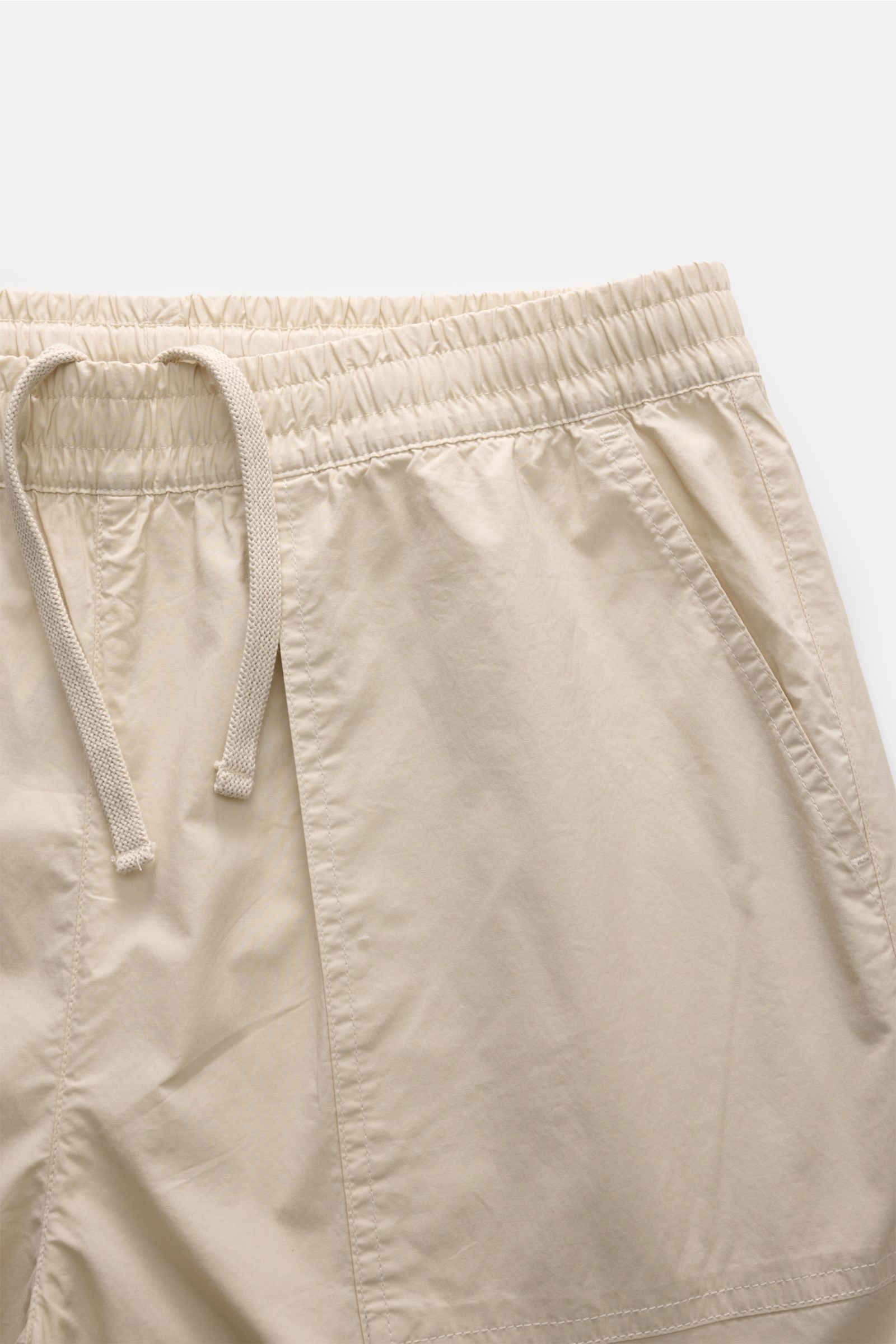 Nahaufnahme von beigen 04651/ A trip in a bag Hosen mit elastischem Bund und Kordelzug, aus schräger Perspektive fotografiert.