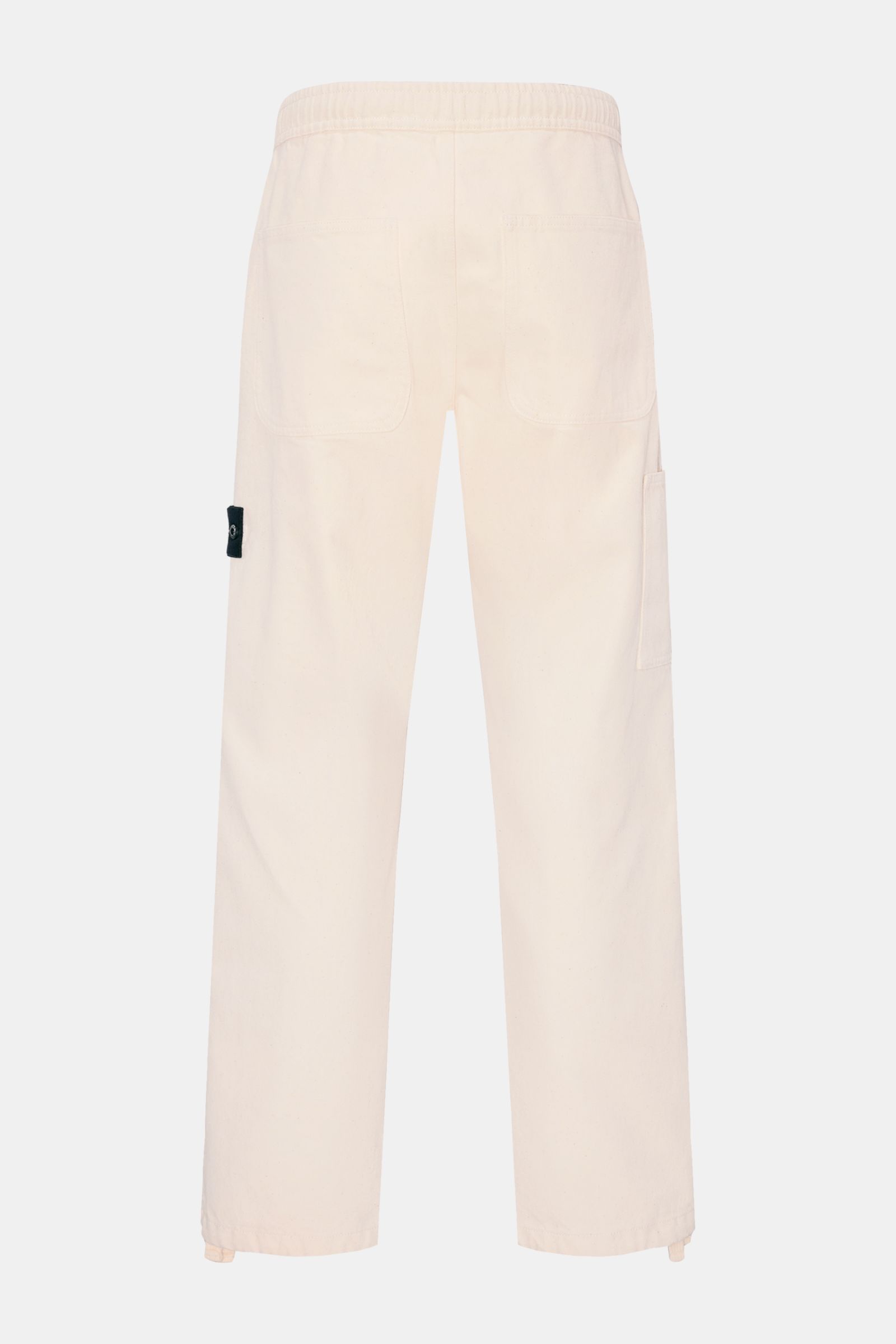Stone Island Jogger pants 'Raw Beauty' cream shown from the back, loose fit pure cotton twill with elastic waistband, patch pockets, adjustable hem, and signature compass badge. 

These robust jogger pants called 'Raw Beauty' by STONE ISLAND are made o