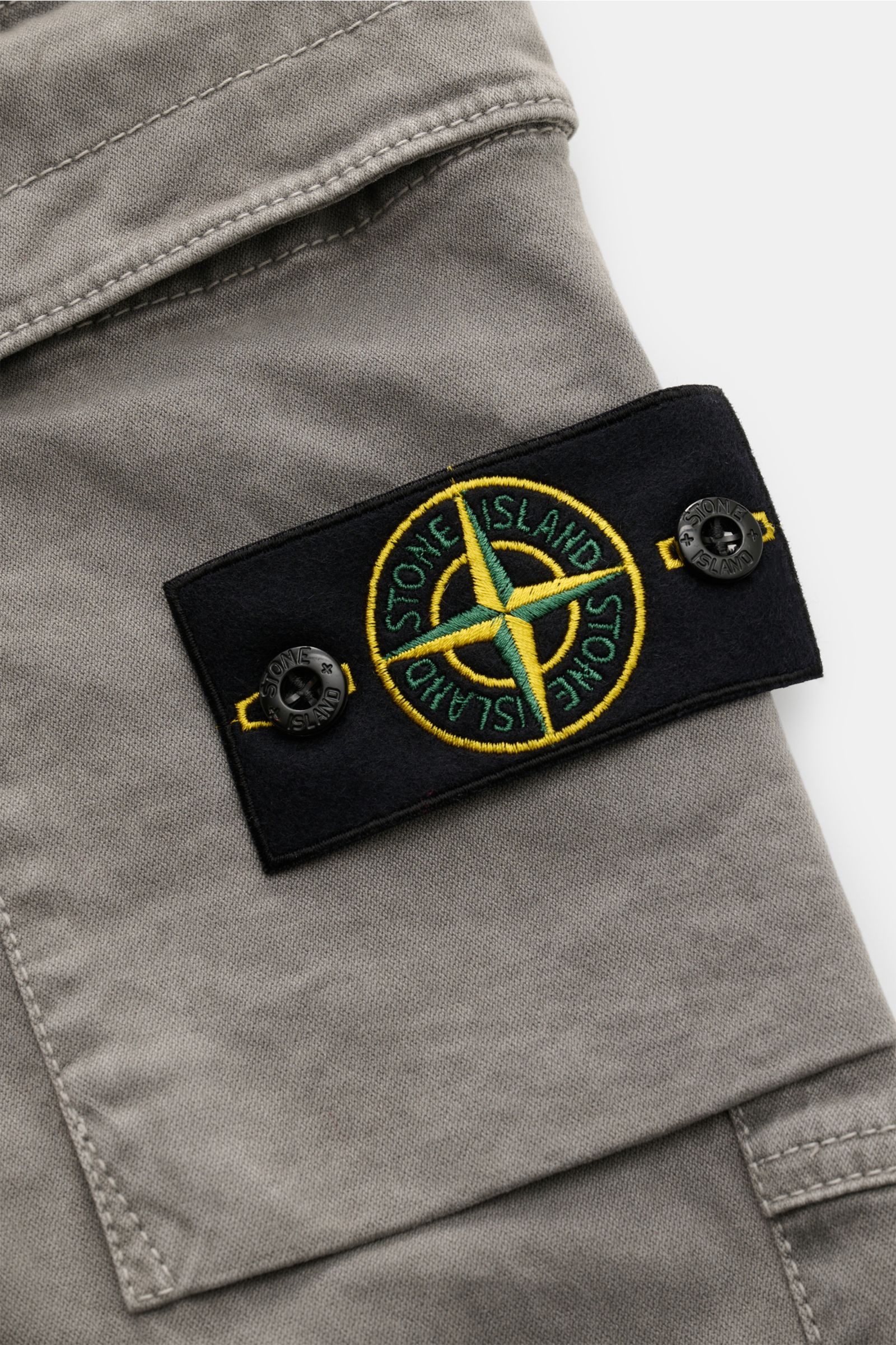 Stone Island Cargo-Jogpants grau, Nahaufnahme der seitlichen Cargo-Tasche mit schwarzem Kompass-Badge, elastische Bio-Baumwolle.