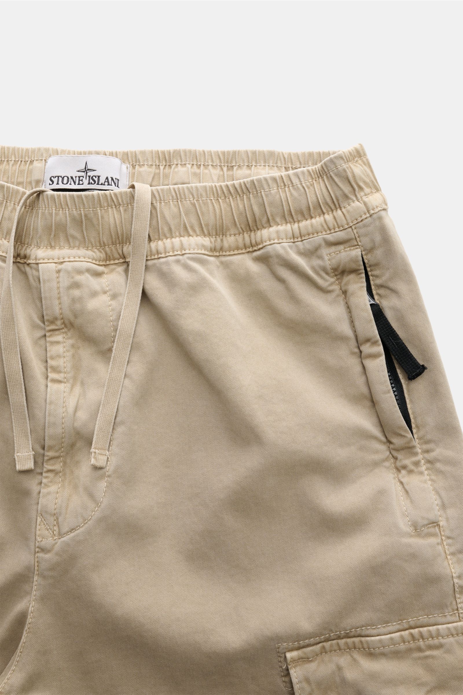 Stone Island Cargo-Jogpants beige, frontale Nahaufnahme, elastischer Bund mit Tunnelzug, Reißverschluss-Taschen, Bio-Baumwolle, urbaner Utility-Look.