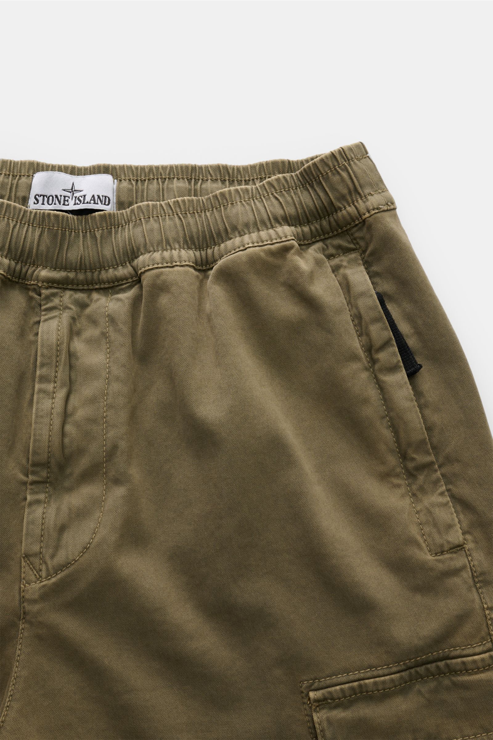 Stone Island Cargo-Jogpants oliv, Detailaufnahme vom elastischen Bund und Taschen, aus stückgefärbter Bio-Baumwolle, Tapered Fit.