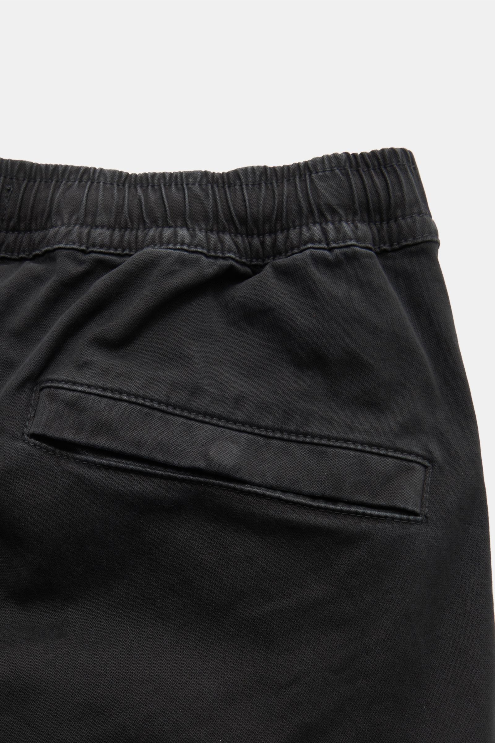 Close-up image of the back upper section of Stone Island Cargo-Joggpants schwarz, photographed from above, showing the elastic waistband with inner drawstring, back pocket with button flap, made of slightly elastic, soft cotton, garment dyed, regular fit,