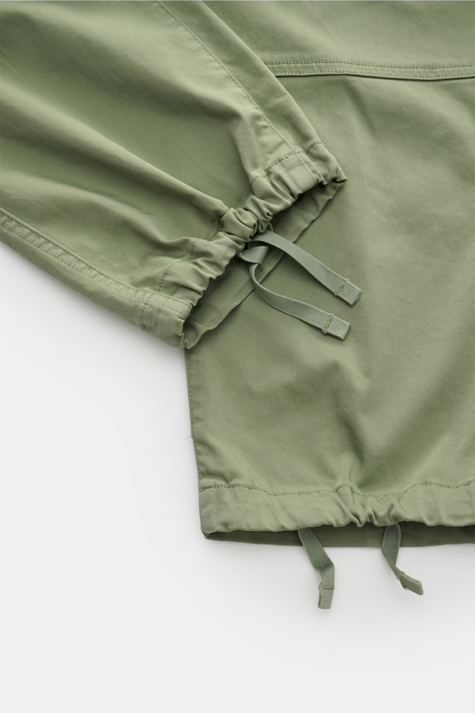 Stone Island Cargohose oliv in Nahaufnahme von unten, zeigt regulierbare Beinabschlüsse mit Zugbändern aus leichter Bio-Baumwolle.