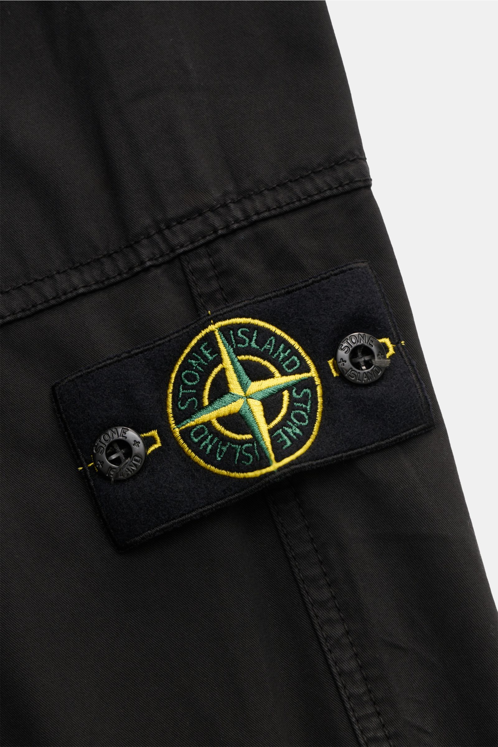 Close-up front-side view of the Stone Island Joggpants schwarz showing the black fabric with the typical compass badge on the elastic waistband. Diese leger geschnittene Joggpants aus hochwertiger, leicht elastischer Baumwolle von STONE ISLAND hat mit ihr