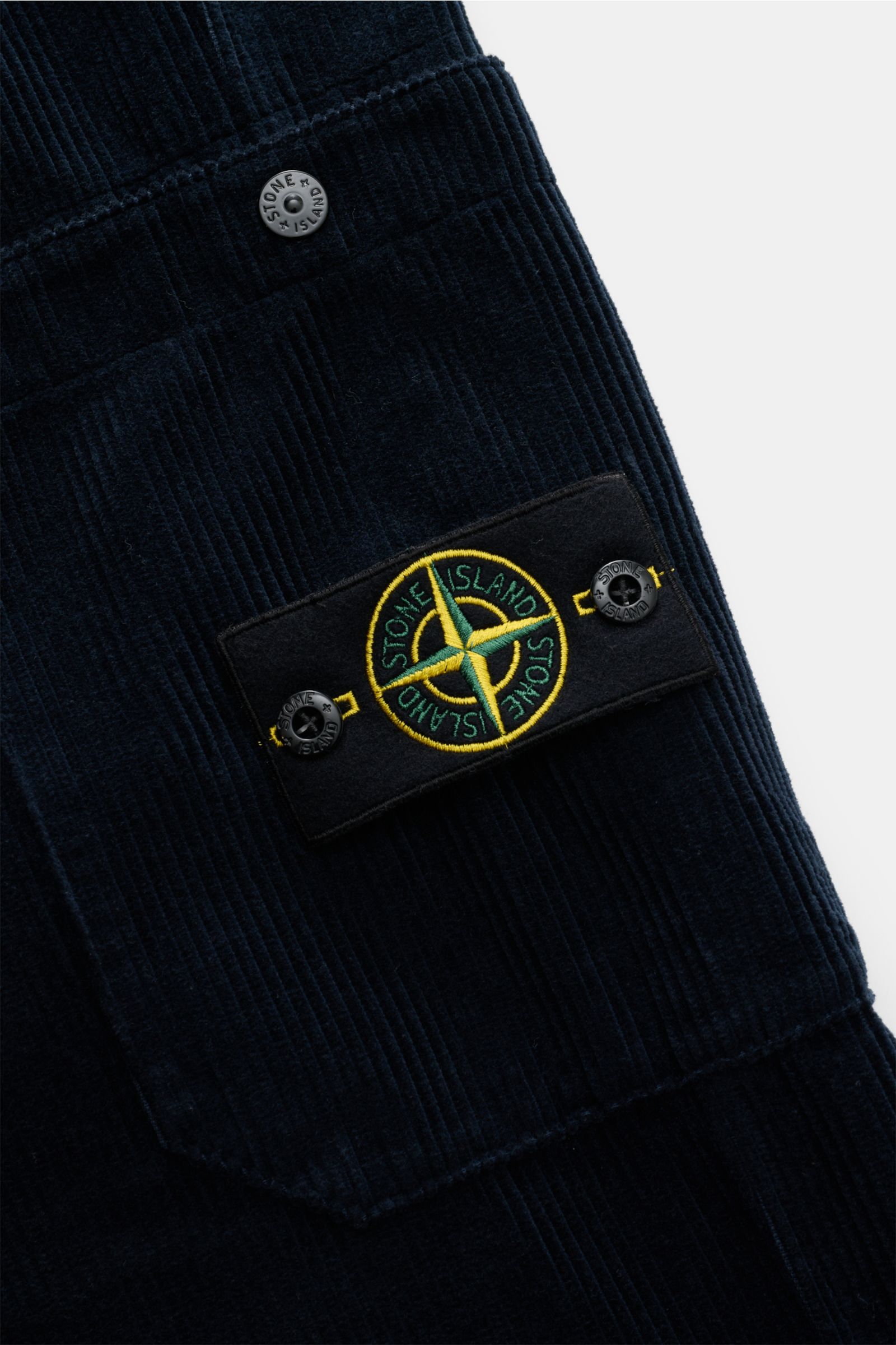 Close-up side view of Stone Island Cord-Cargohose navy showing soft organic cotton corduroy fabric, functional side cargo pocket with snap button, and iconic compass badge.

Lässig und unverkennbar STONE ISLAND: Diese Cargohose kombiniert soften Cord a