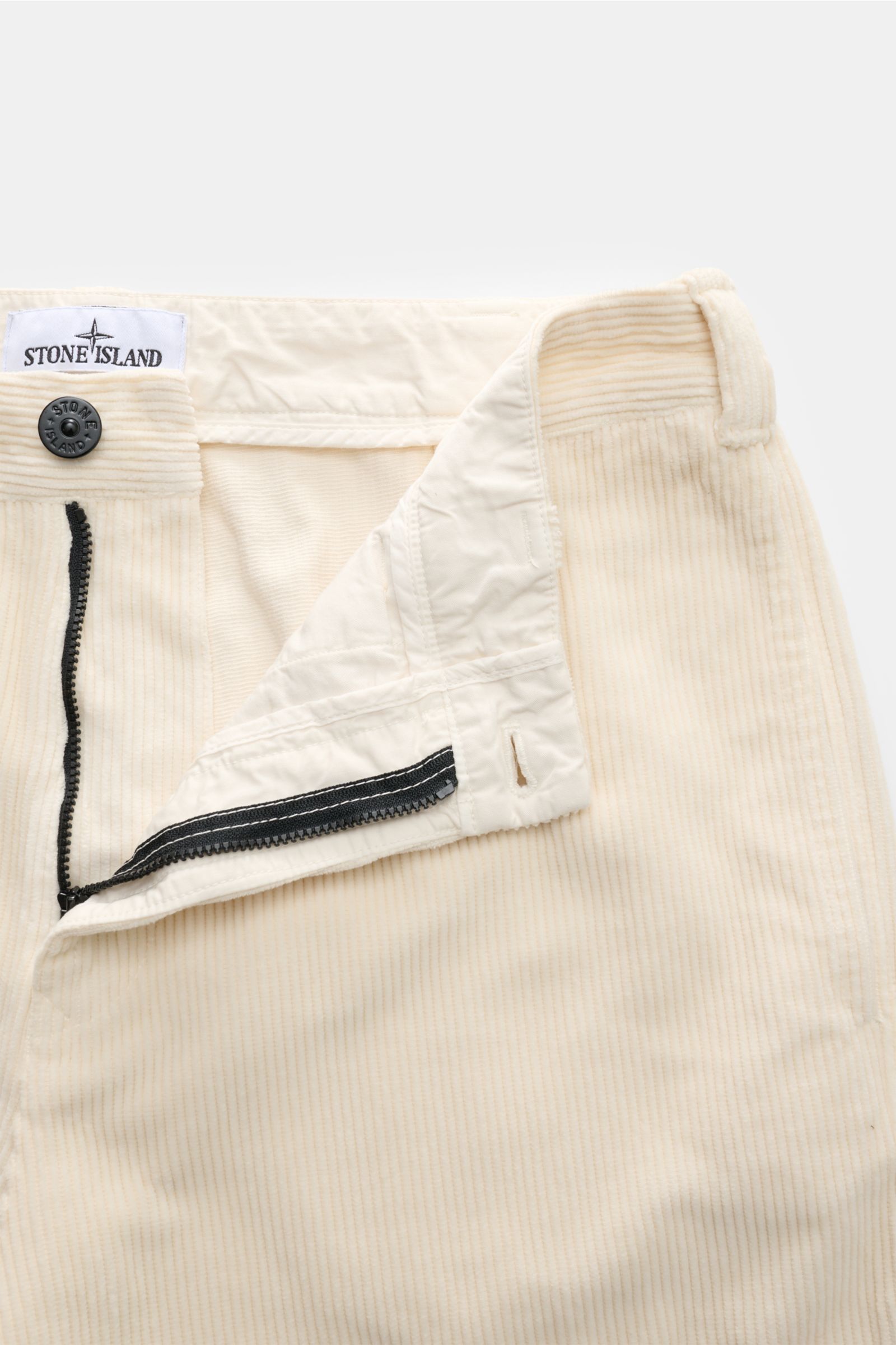 Stone Island Cord-Cargohose creme, Detailaufnahme von vorne mit offenem Reißverschluss, weicher Bio-Baumwoll-Cord, Regular Fit, Kompass-Badge.