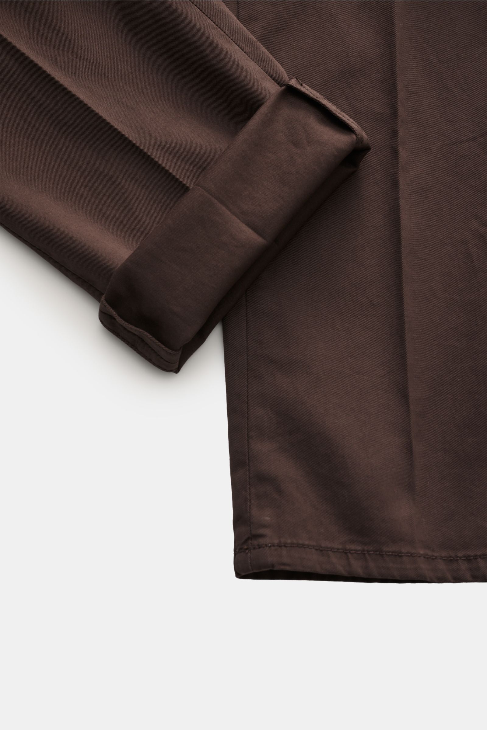 Brunello Cucinelli Chino 'Italian Fit' dunkelbraun shown from a close-up side angle, highlighting the folded leg cuff and fine twill cotton fabric texture. Die Chino im 'Italian Fit' des Luxuslabels BRUNELLO CUCINELLI ist ein vielseitig kombinierbarer 