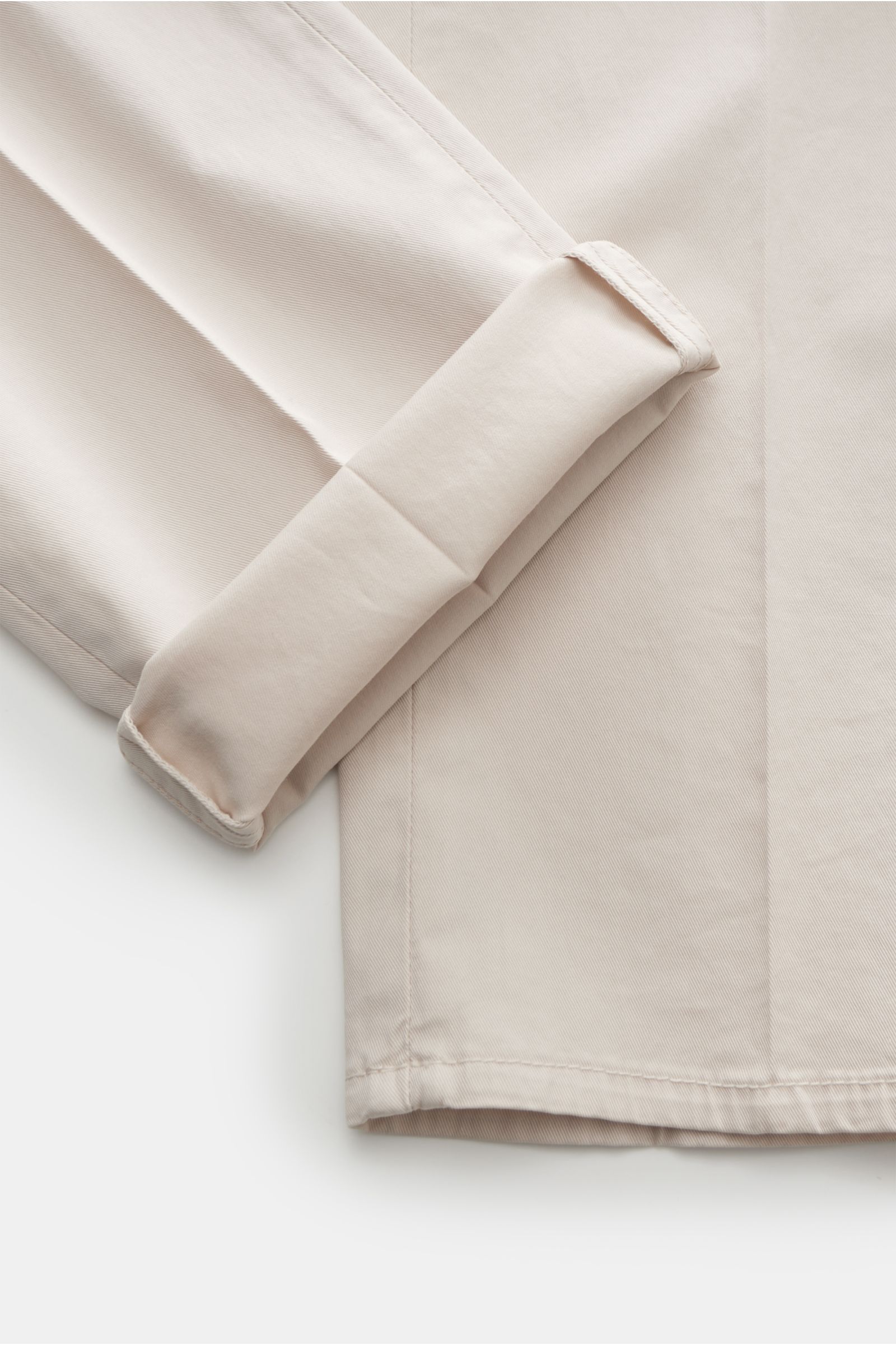 Close-up of the cuff and hem of the Brunello Cucinelli Chino 'Italian Fit' sand, photographed from a top-down perspective, showcasing twill cotton fabric, slight elasticity, soft touch, regular slim fit, zipper and button closure, French pockets, small wa