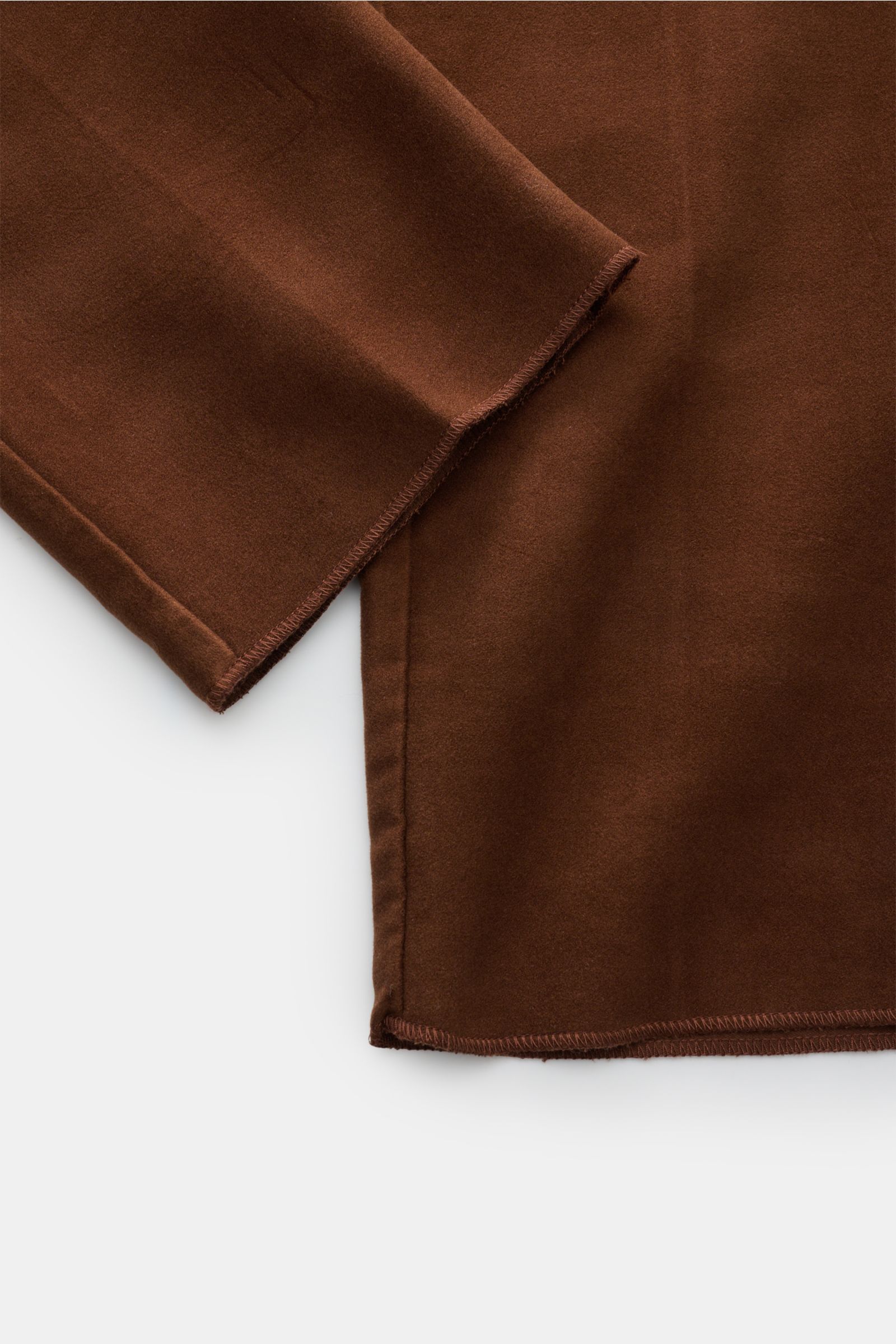 Nahaufnahme der offenen Beinenden der Doppiaa Hose 'Aantioco' braun aus softem Fleece mit offenem Saum, von oben fotografiert.