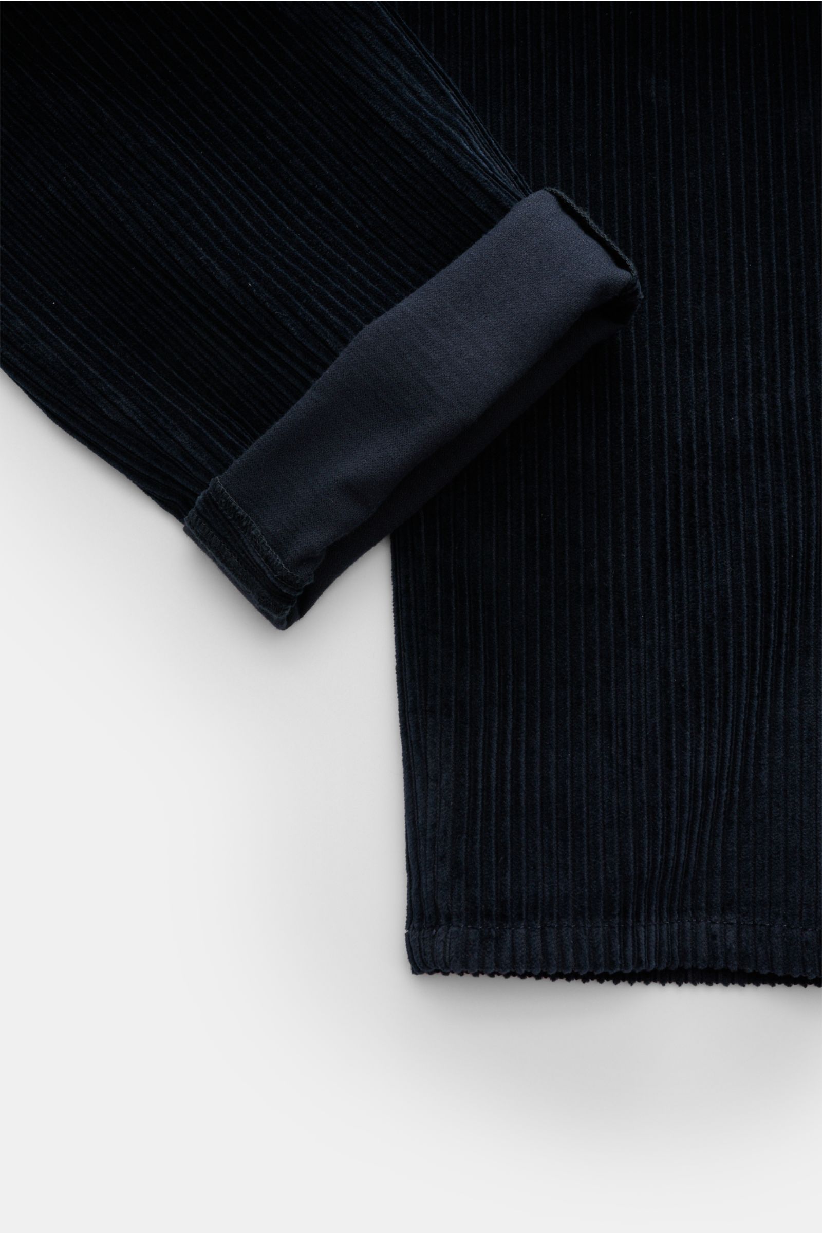 Close-up shot from above of Dondup Cordhose 'Gaubert' navy showing folded hem and wide cotton corduroy fabric with soft texture and slight stretch. Das beliebte Modell 'Gaubert' von DONDUP präsentiert das italienische Label hier als moderne Cordhose, d