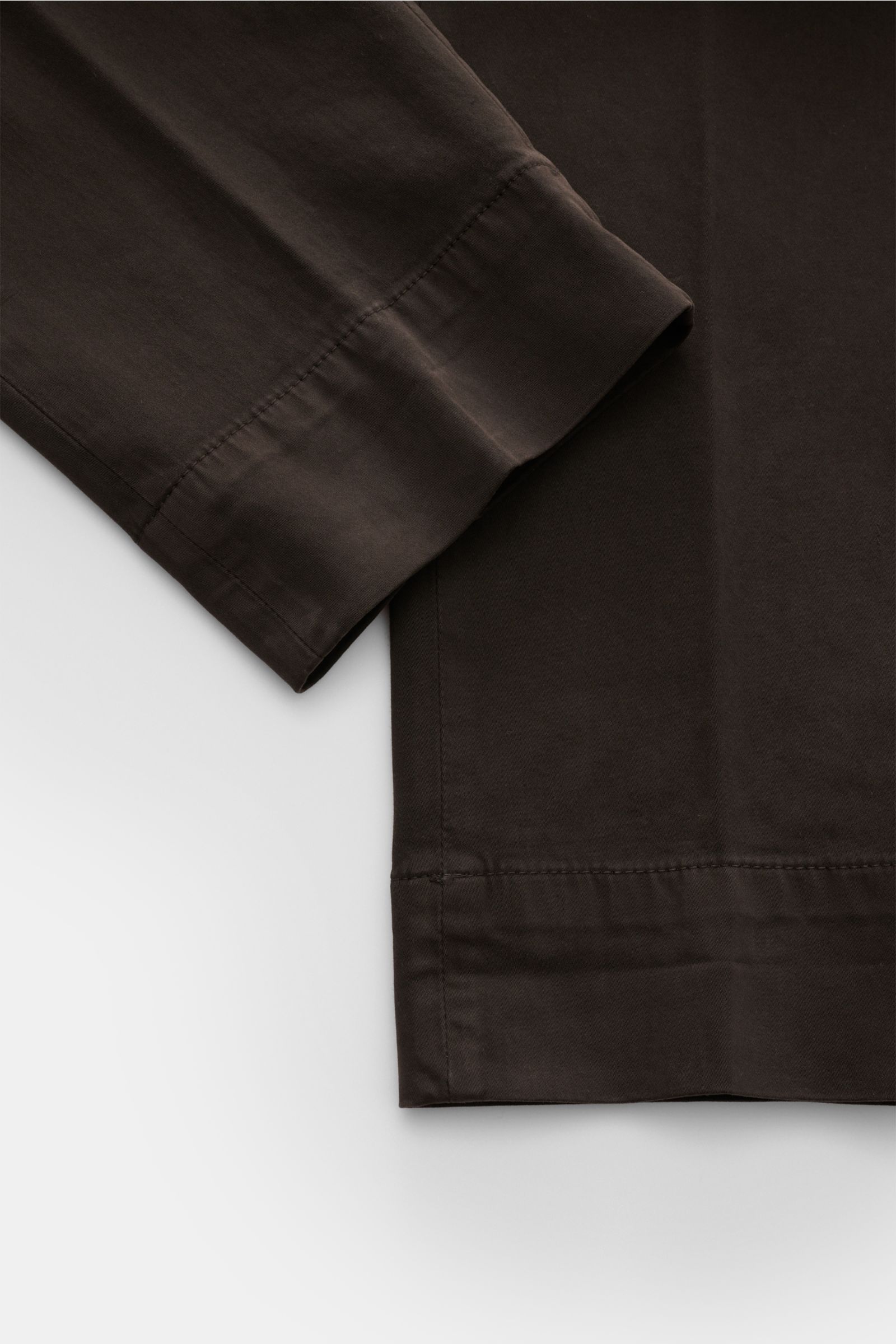 Nahaufnahme der Briglia 1949 Baumwollhose dunkelbraun, schmal zulaufend, aus elastischer Baumwolle mit weichem Griff, Reißverschluss, Bundknopf und französischen Taschen, fotografiert von oben.