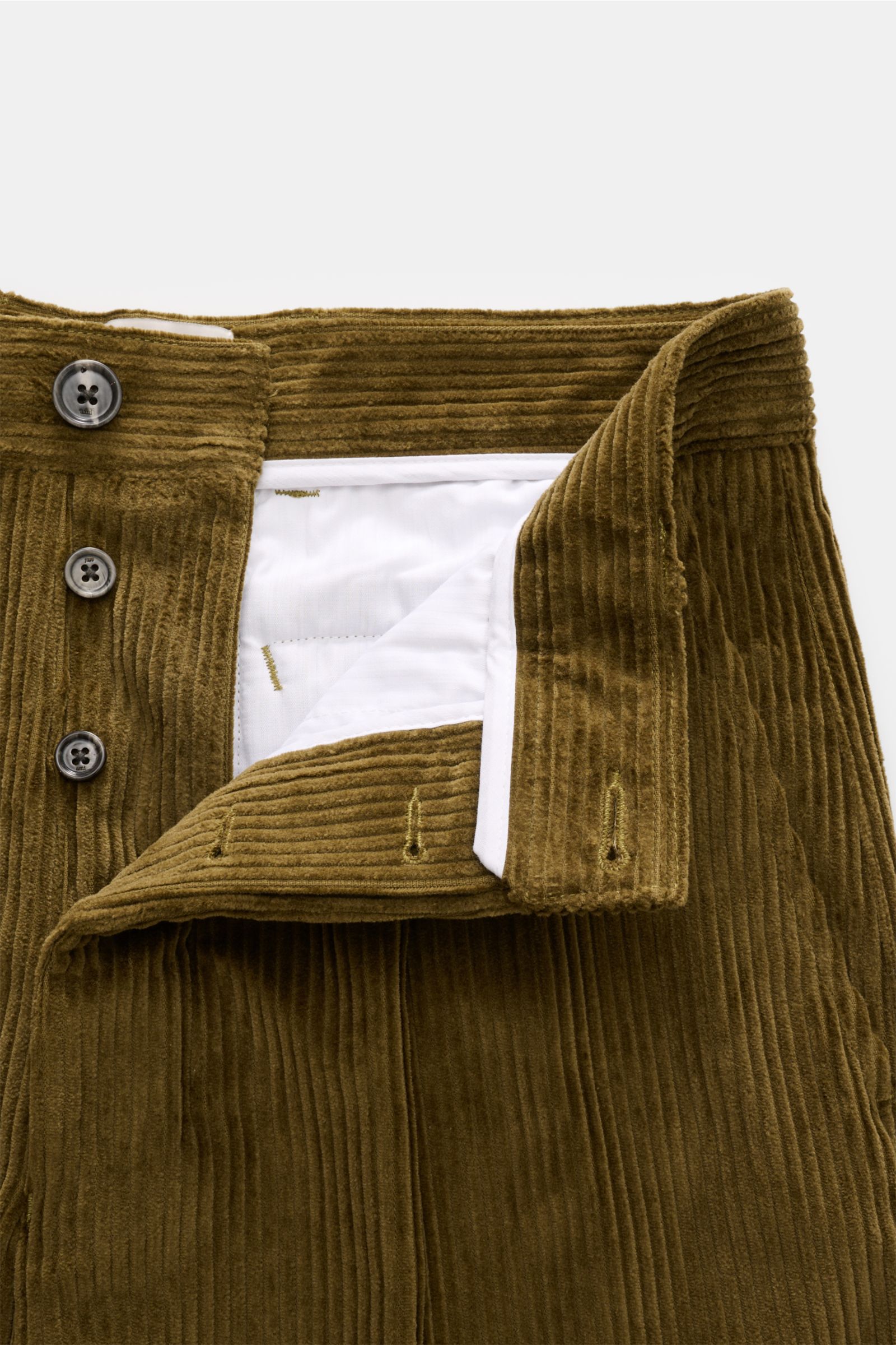 Close-up front view of Ami Paris Cordhose oliv in olive green corduroy with button fly, wide ribs, and white inner lining, showing detailed waistband.

Description: Mit lässiger Eleganz und französischem Esprit verleiht diese Karottenhose von AMI PARIS