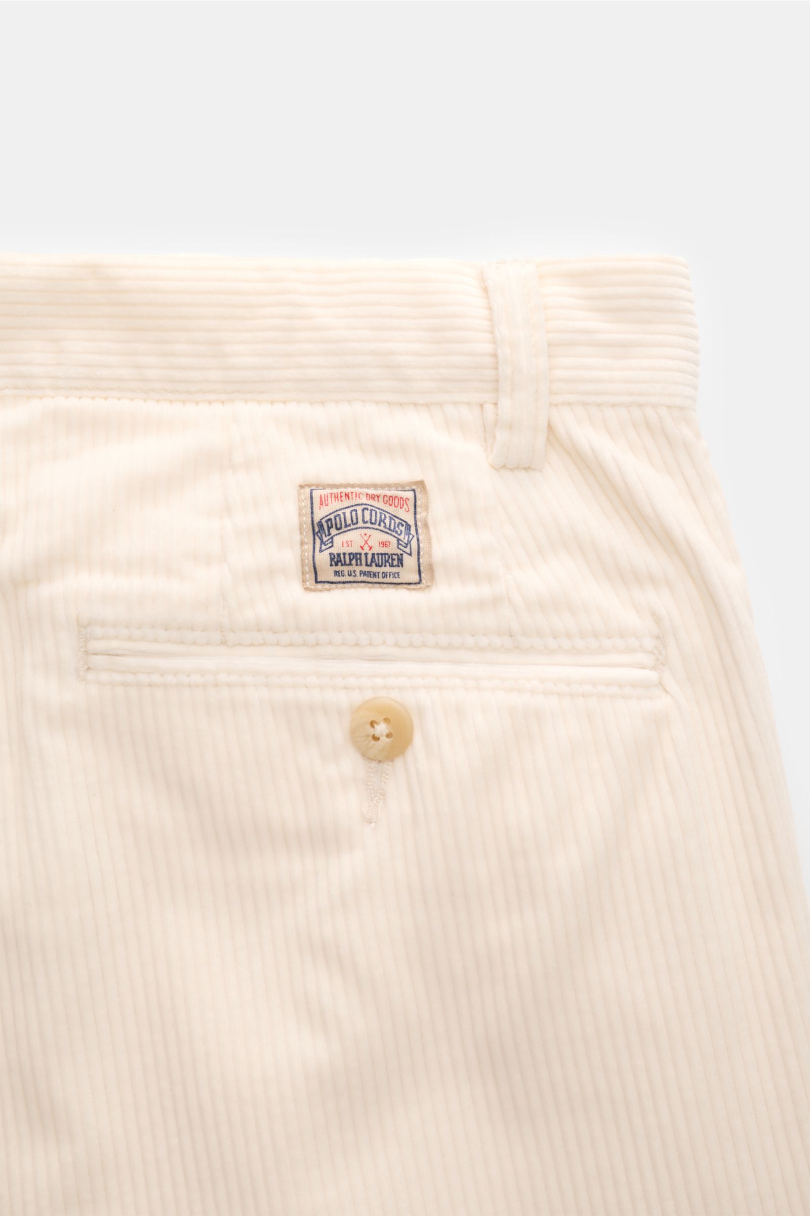 Close-up rear view of Polo Ralph Lauren Cordhose creme corduroy pants showing buttoned back pocket and small logo patch on waistband.