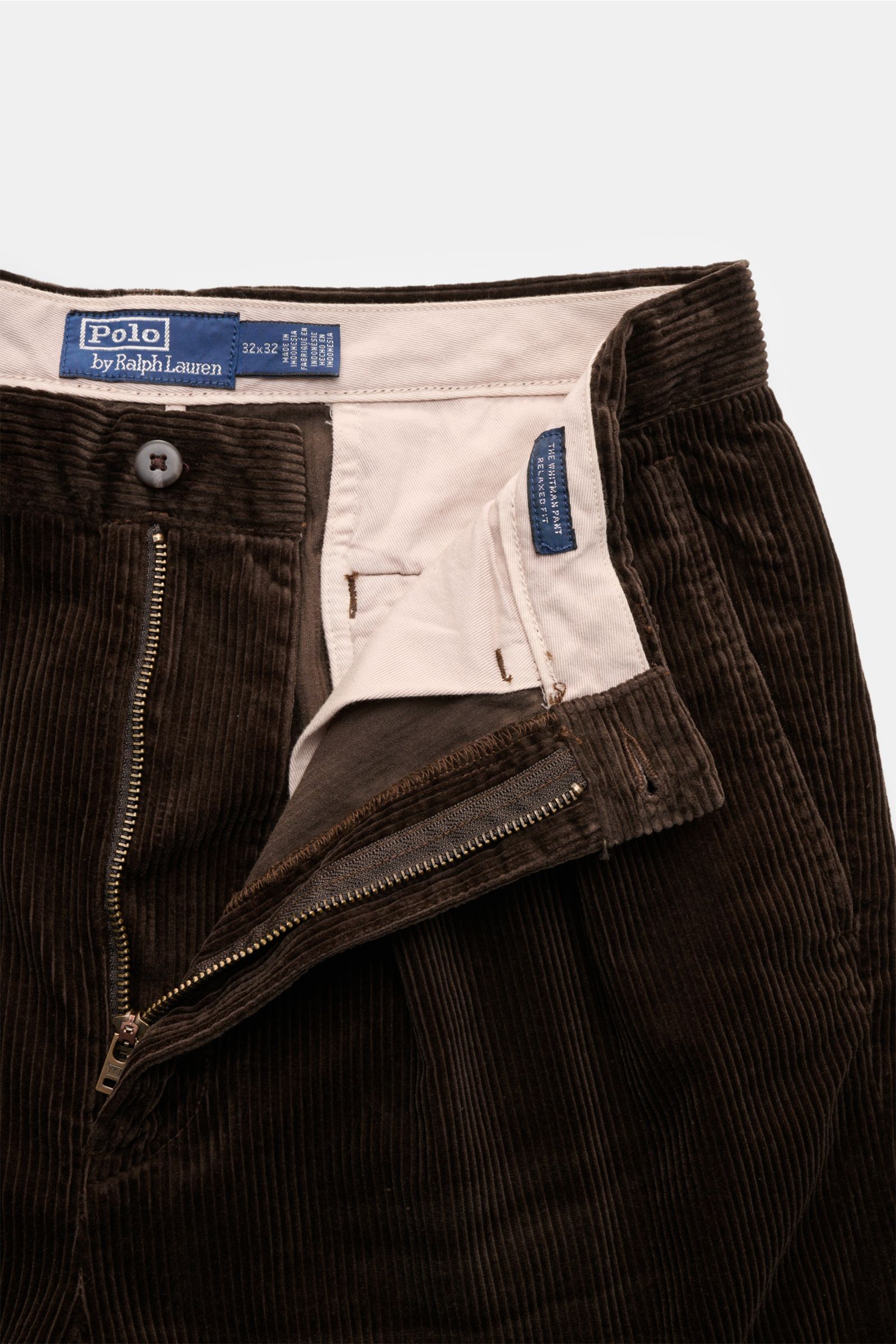 Polo Ralph Lauren Cordhose dunkelbraun aus Baumwolle mit Bundfalten, Reißverschluss, Knöpfen, Uhrentasche, Saumaufschlag, frontal nah fotografiert.