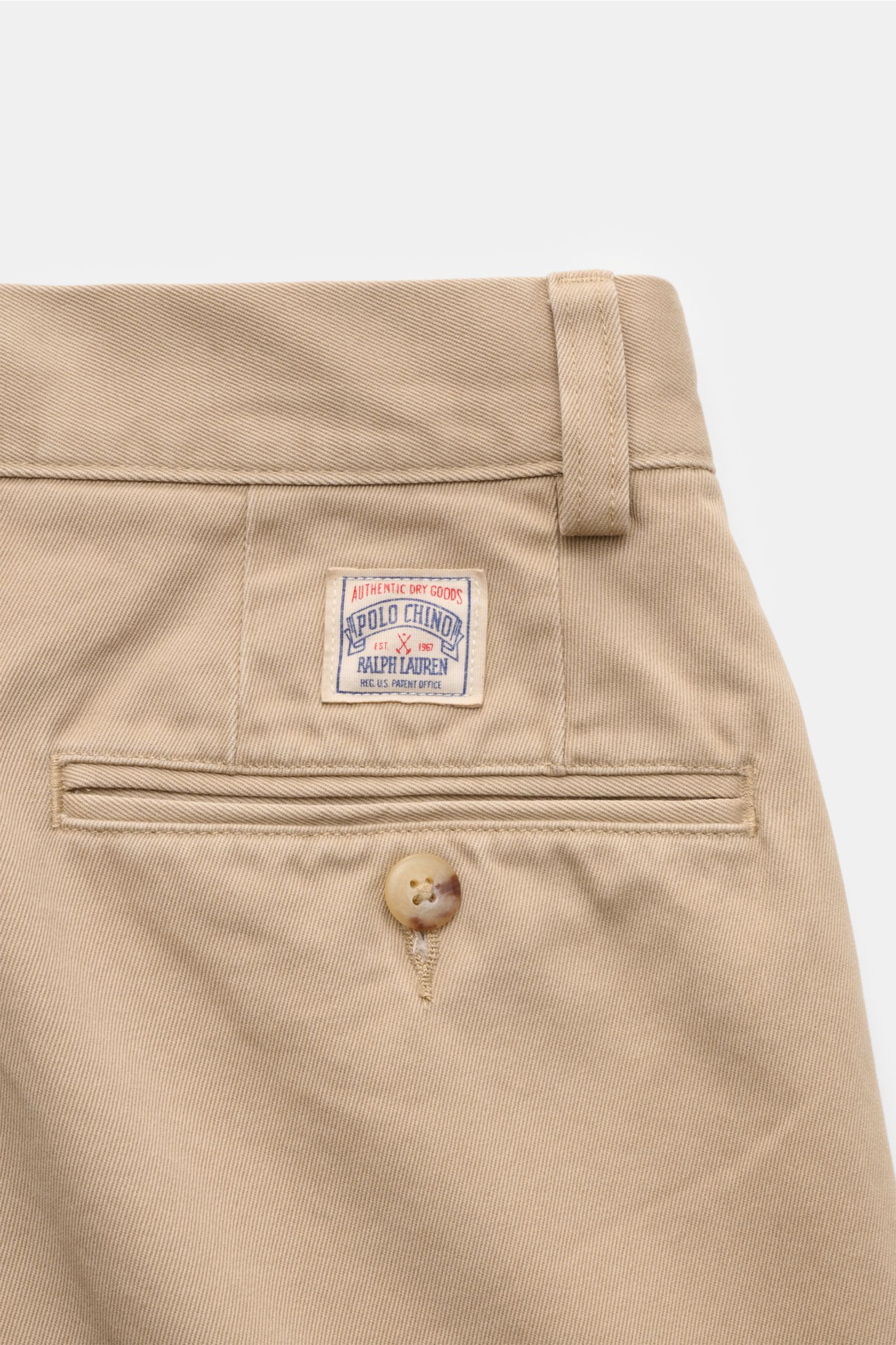 Close-up rear view of the Polo Ralph Lauren Chino 'Whitman' beige, showing back pocket with button, small brand patch, and belt loop on twill cotton fabric. Der perfekte Begleiter für entspannte, smarte Looks: Die stückgefärbte 'Whitman' von POLO RALPH