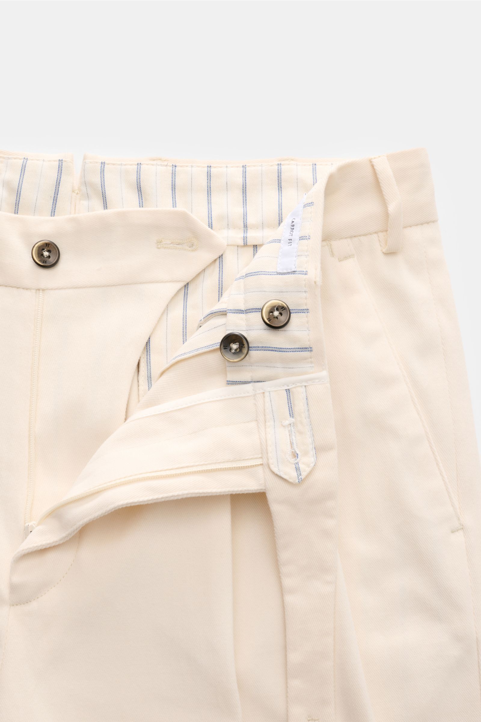 Close-up from the front top view of the PT Torino Chino 'Carrot Fit' creme with open waistband showing buttons, extended button fly, and striped inner lining, made from soft, slightly elastic cotton twill with stylish pleats and tapered fit for classic el