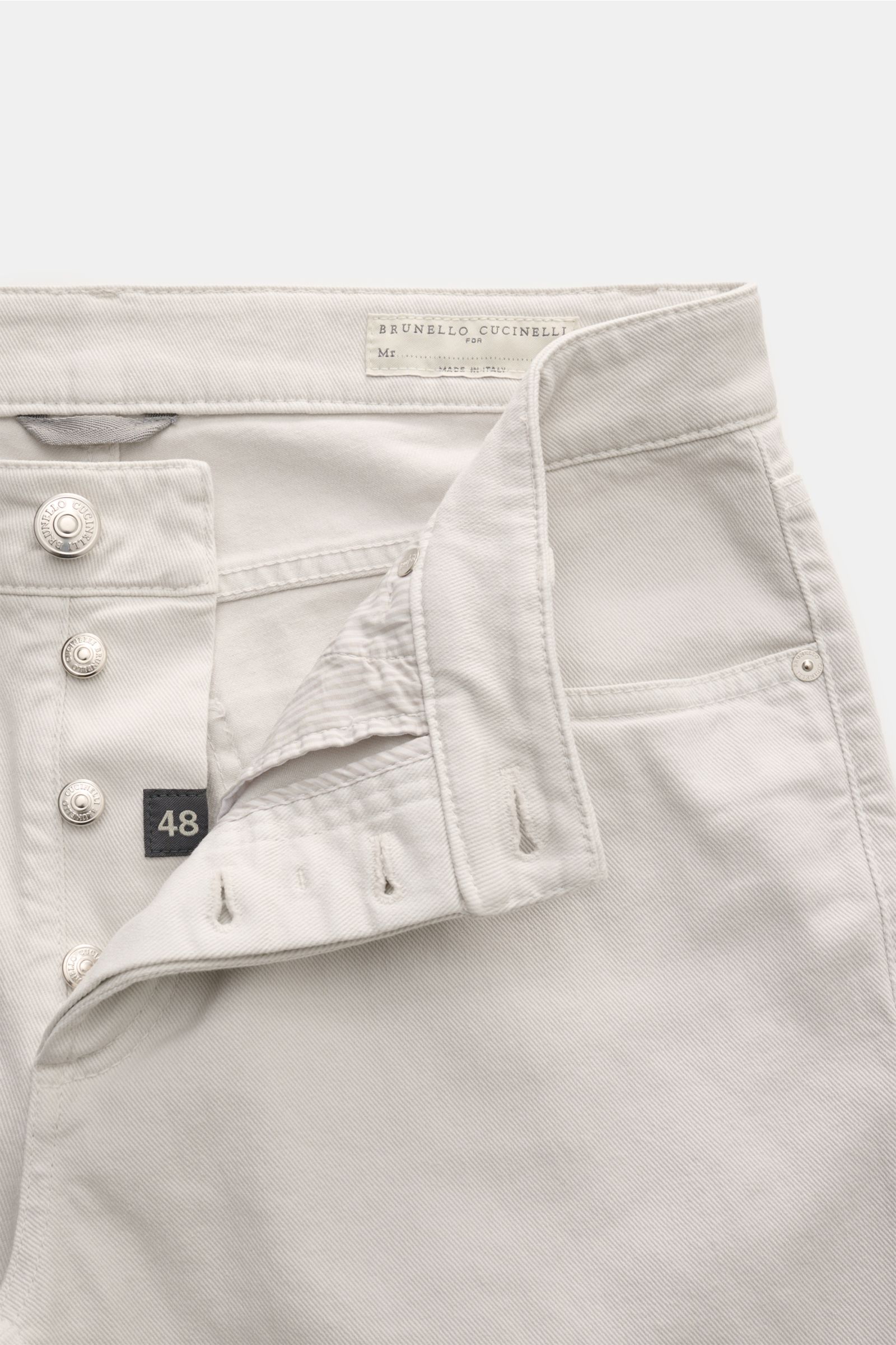 Brunello Cucinelli Jeans 'Traditional Fit' sand, Nahaufnahme von vorne mit offenem Button Fly, Five-Pocket-Stil, Lederpatch und Logo-Stitching.