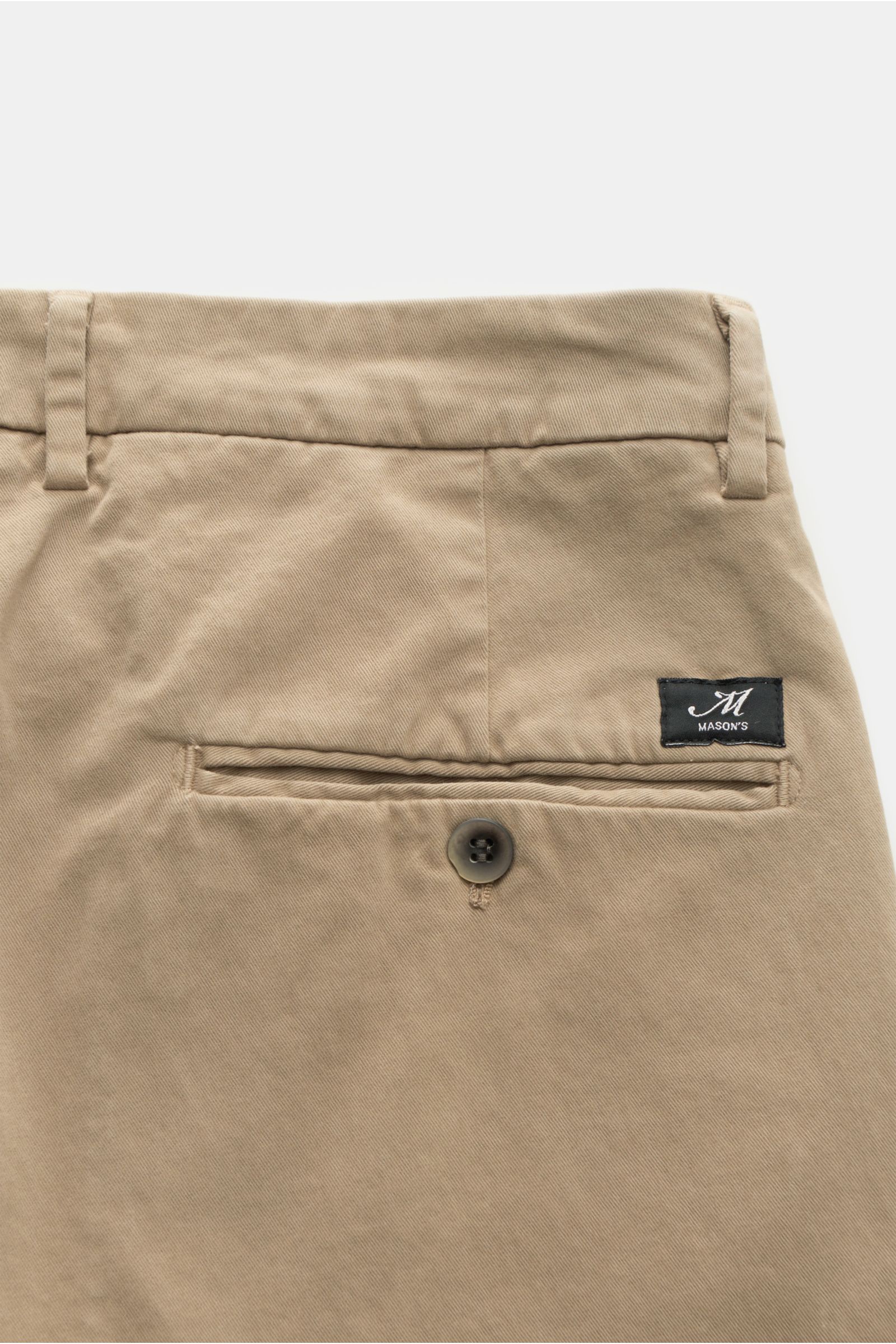 Back view close-up of Mason's Chino 'Torino Style' taupe pants, showing twill cotton fabric, slim fit, low waist, tapered cut, zip fly, buttoned welt back pocket, French pockets, soft touch, garment dyed, and slight stretch quality.