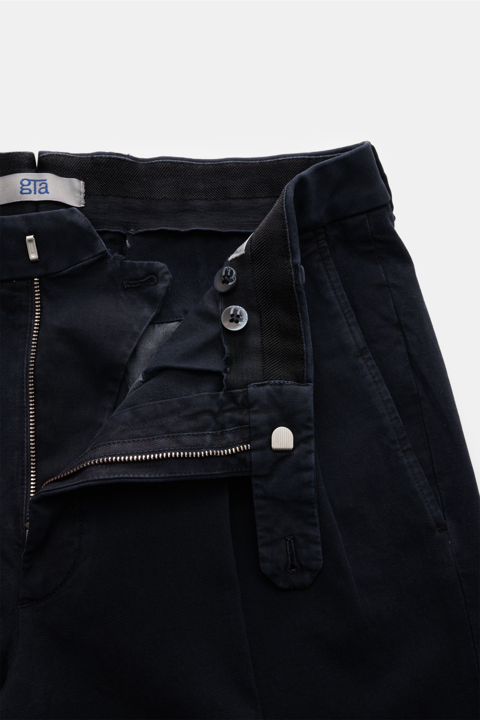 Close-up front view of the navy GTA Hose 'Luca' showing zipper, buttons, double waistband pleat, and soft cotton-modal fabric with slight stretch.