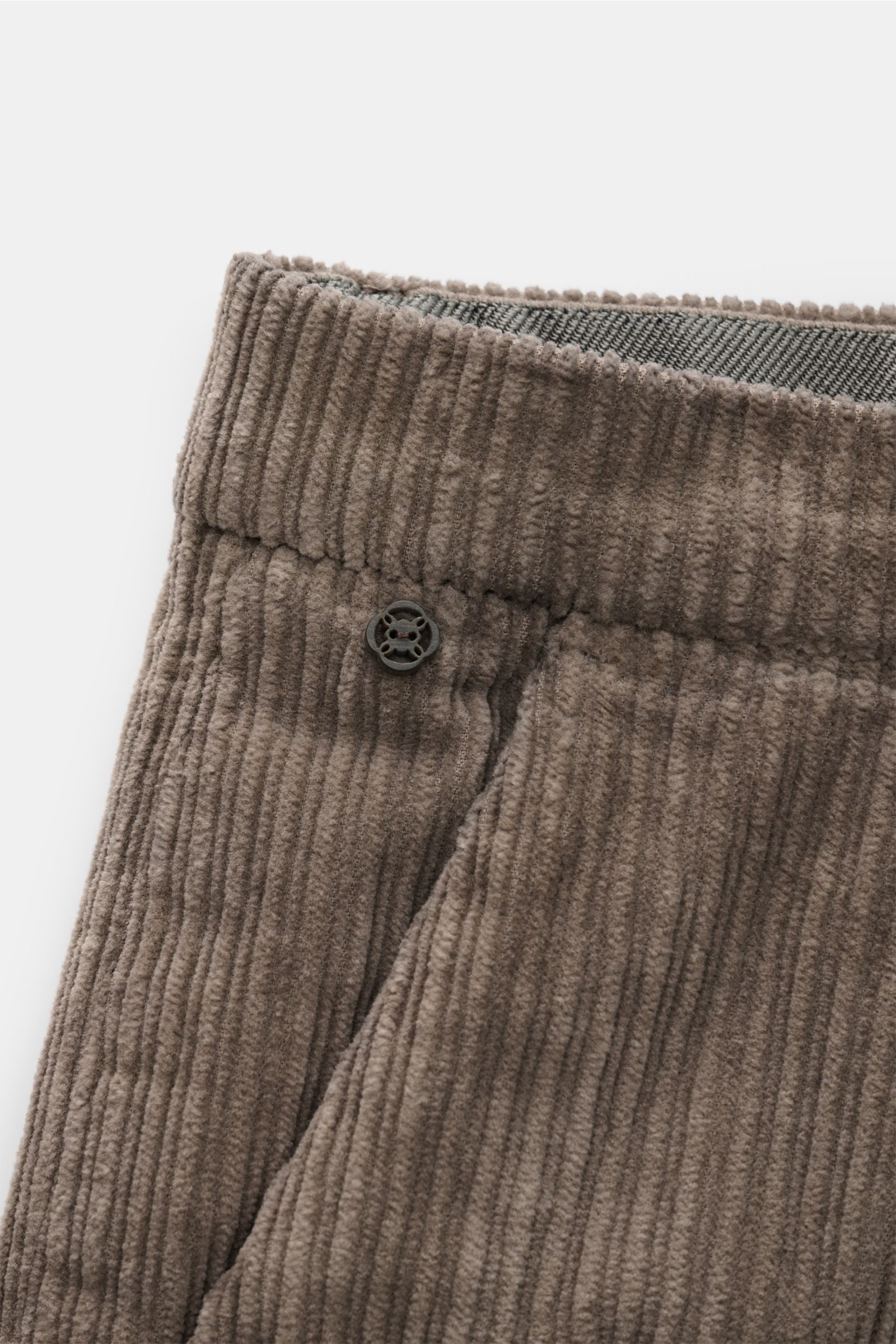 Close-up front view of GTA Cordhose 'Silvio' taupe showing soft cotton cord fabric with light elasticity, regular fit, elastic waistband insert, zipper and button closure, simple front crease, French pockets, and welt pockets at the back.