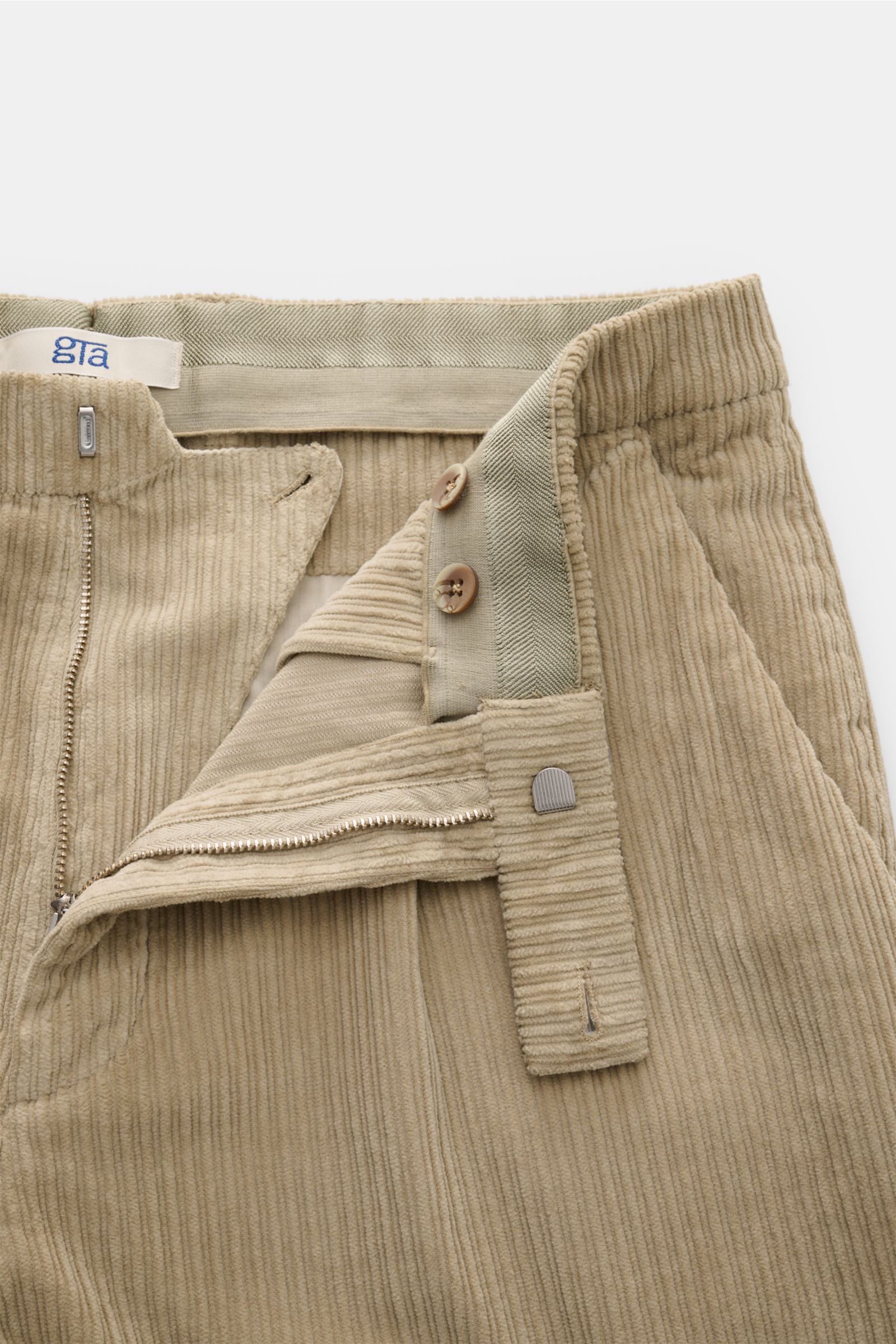 Close-up front view of the GTA Cordhose 'Silvio' beige showing cotton cord fabric, lightly elastic quality, soft touch, regular fit, slightly tapered, zipper and waistband button, elastic waistband insert, simple front crease, French pockets, and welt bac